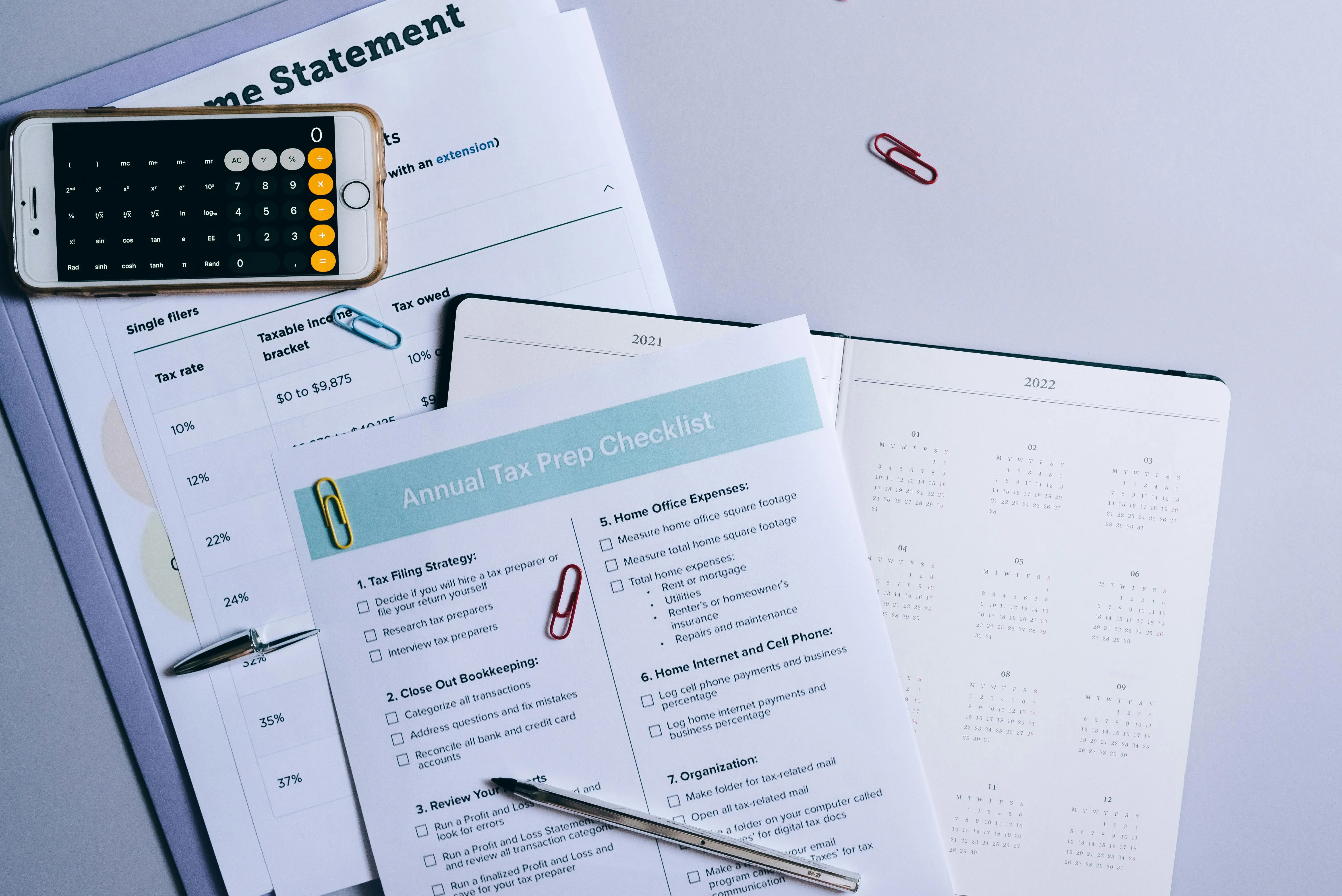 Tax documents on a table with a pen and phone calculator