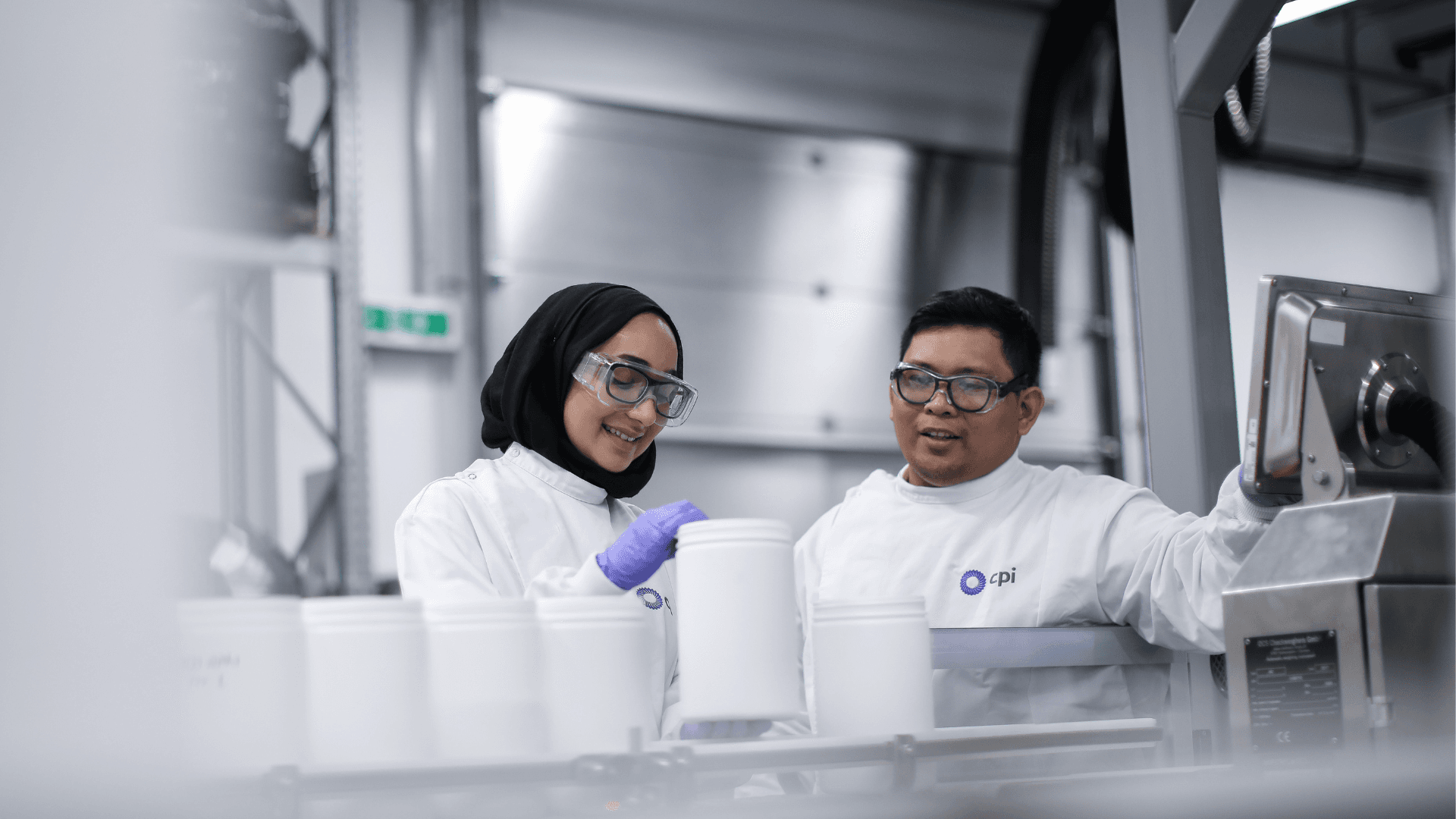 Two CPI experts inspecting white plastic cylinders.