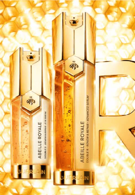 Two gold perfume bottles in gold infront of a gold background