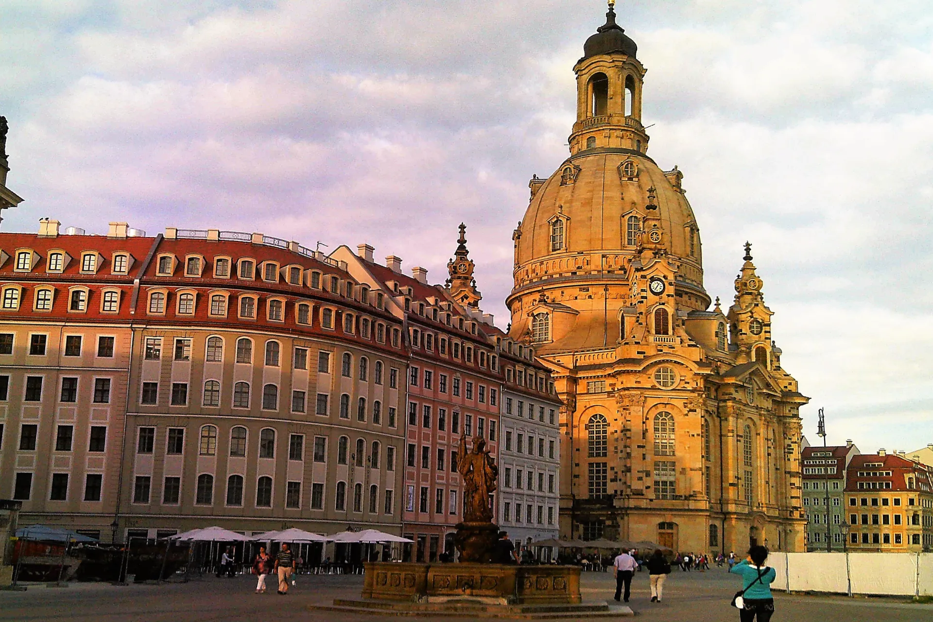Historisches Gebäude mit einem großen Uhrturm unter einem pastellfarbenen Himmel, das aufwendige architektonische Details zeigt.