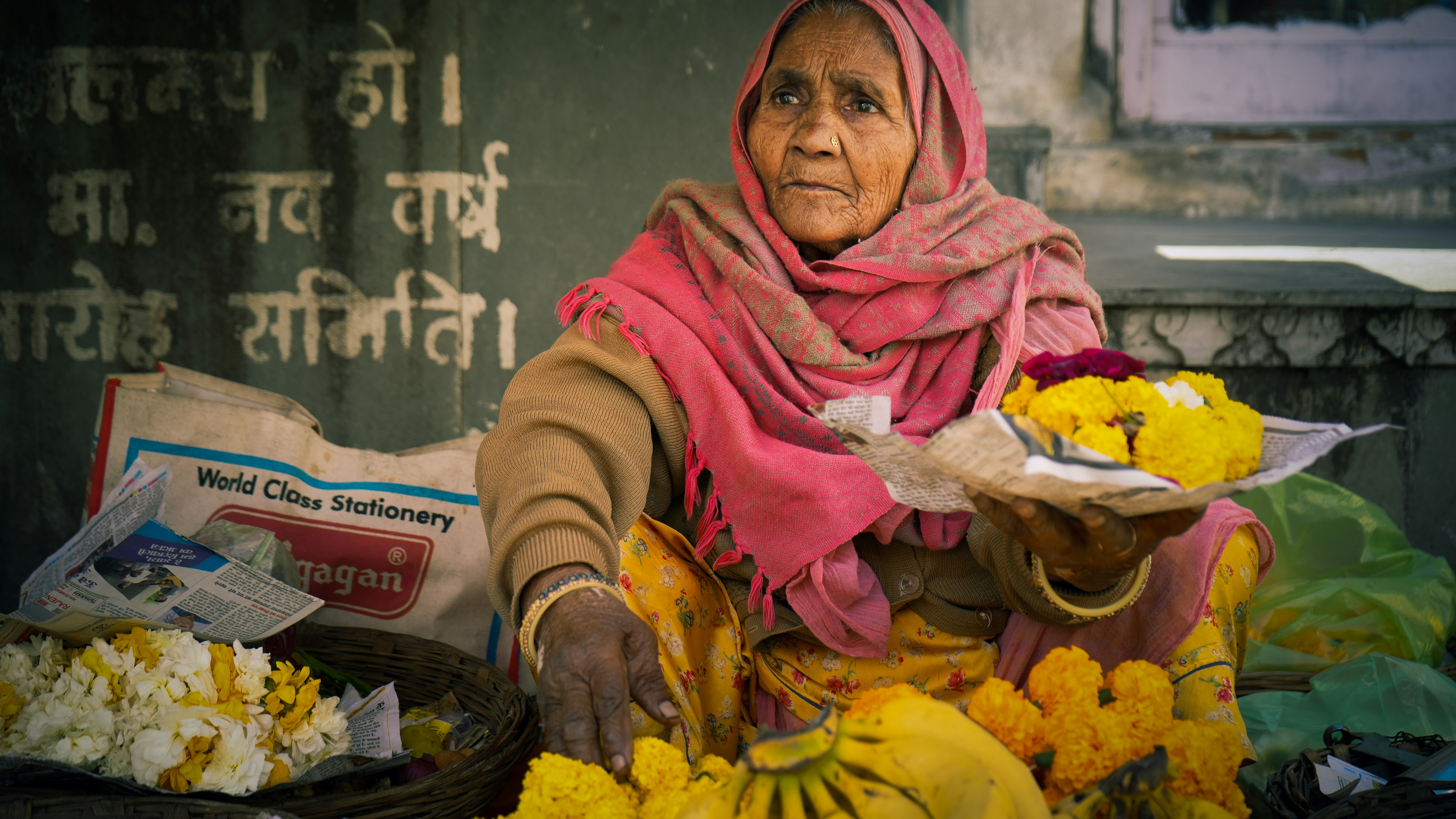 Elderly woman selling flowers and fruit