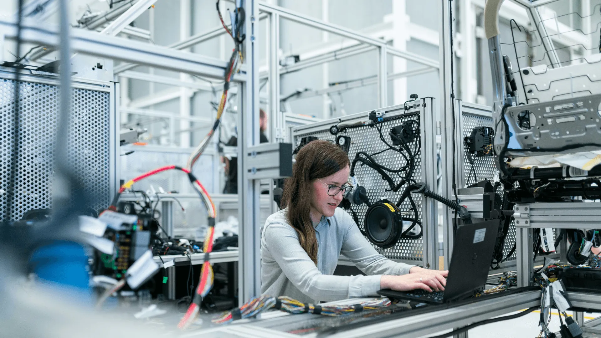 A woman at a laptop in a manufacturing plant