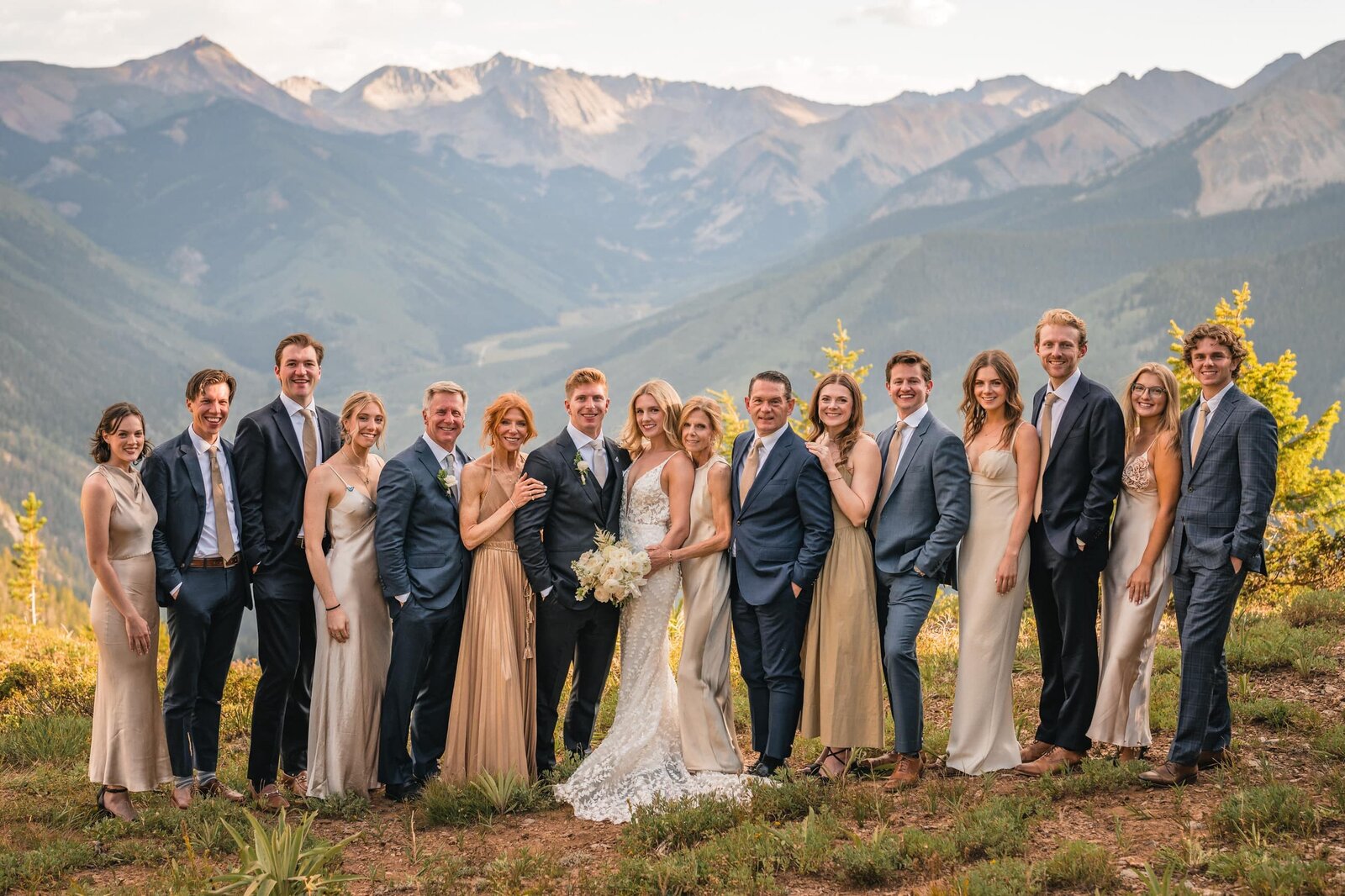Newlyweds posing with a large group at a mountain overlook