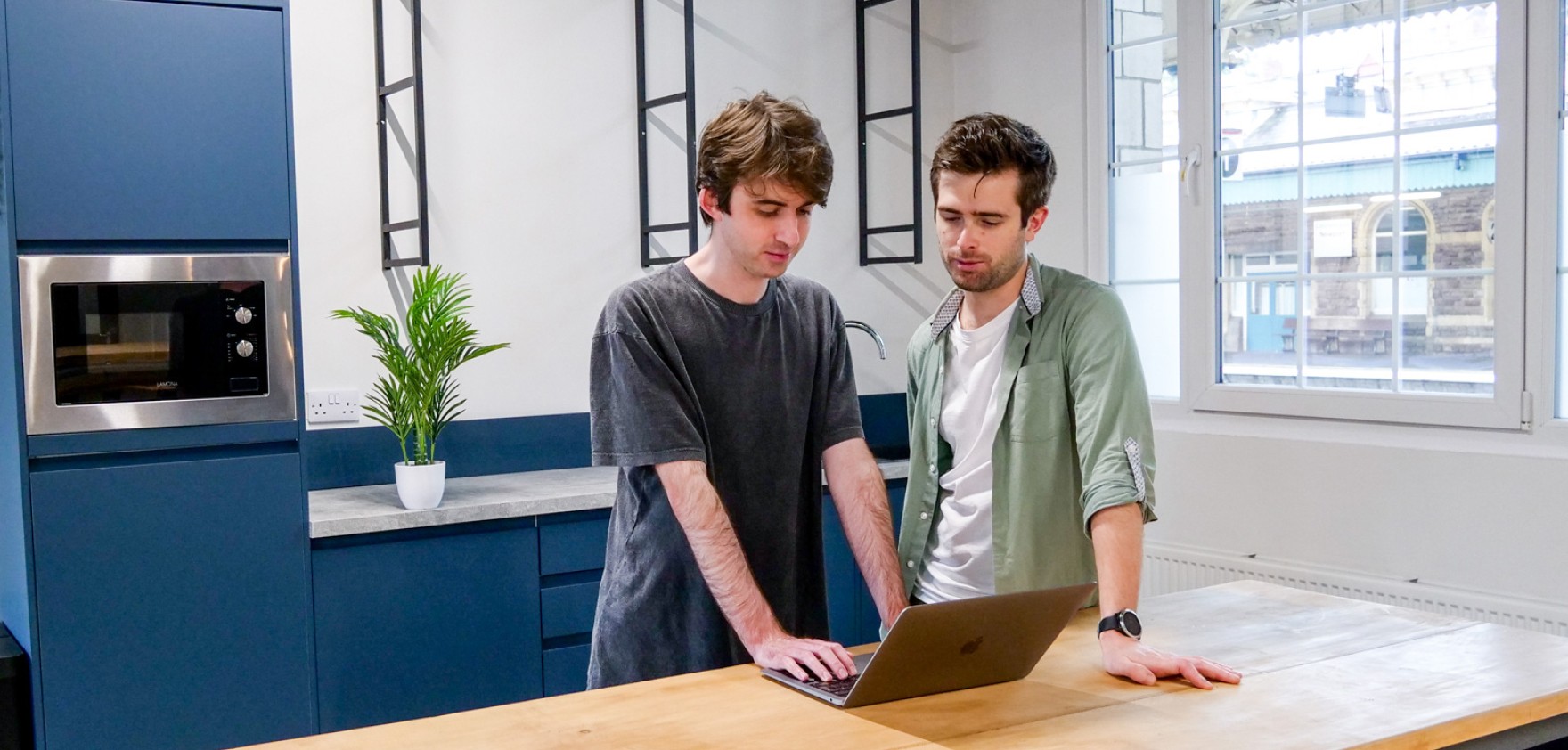 Two people in a kitchen with an open laptop.