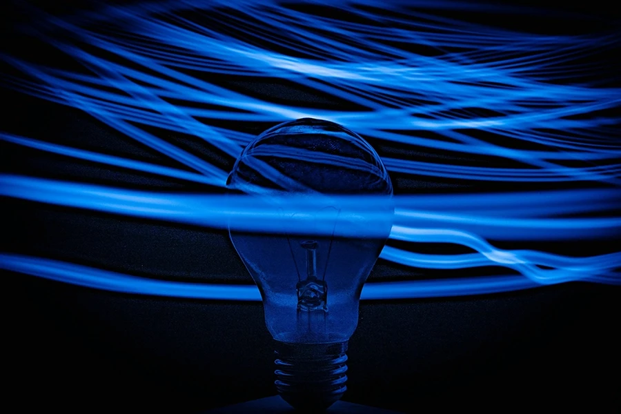 Light bulb silhouette with flowing blue light streaks on a dark background.