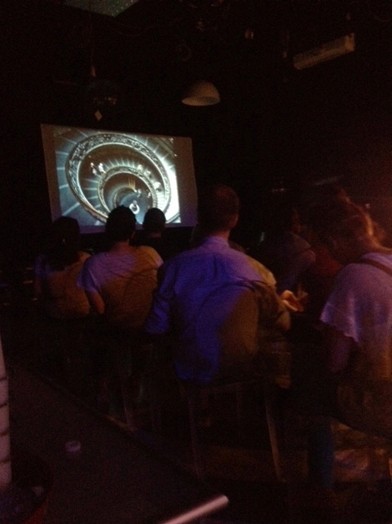dark classroom with people seated and projected vatican imageon screen