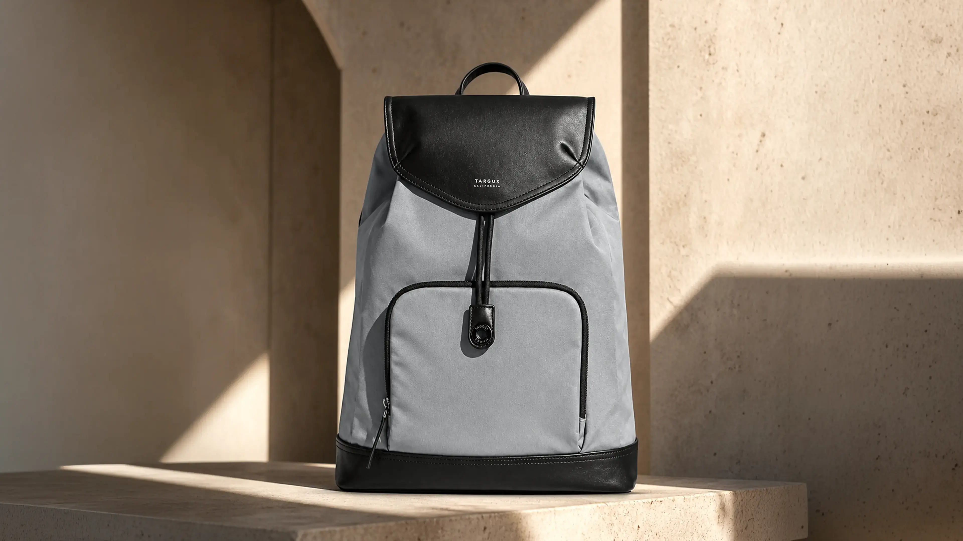 Gray-and-black Targus Newport backpack displayed against warm concrete architecture.