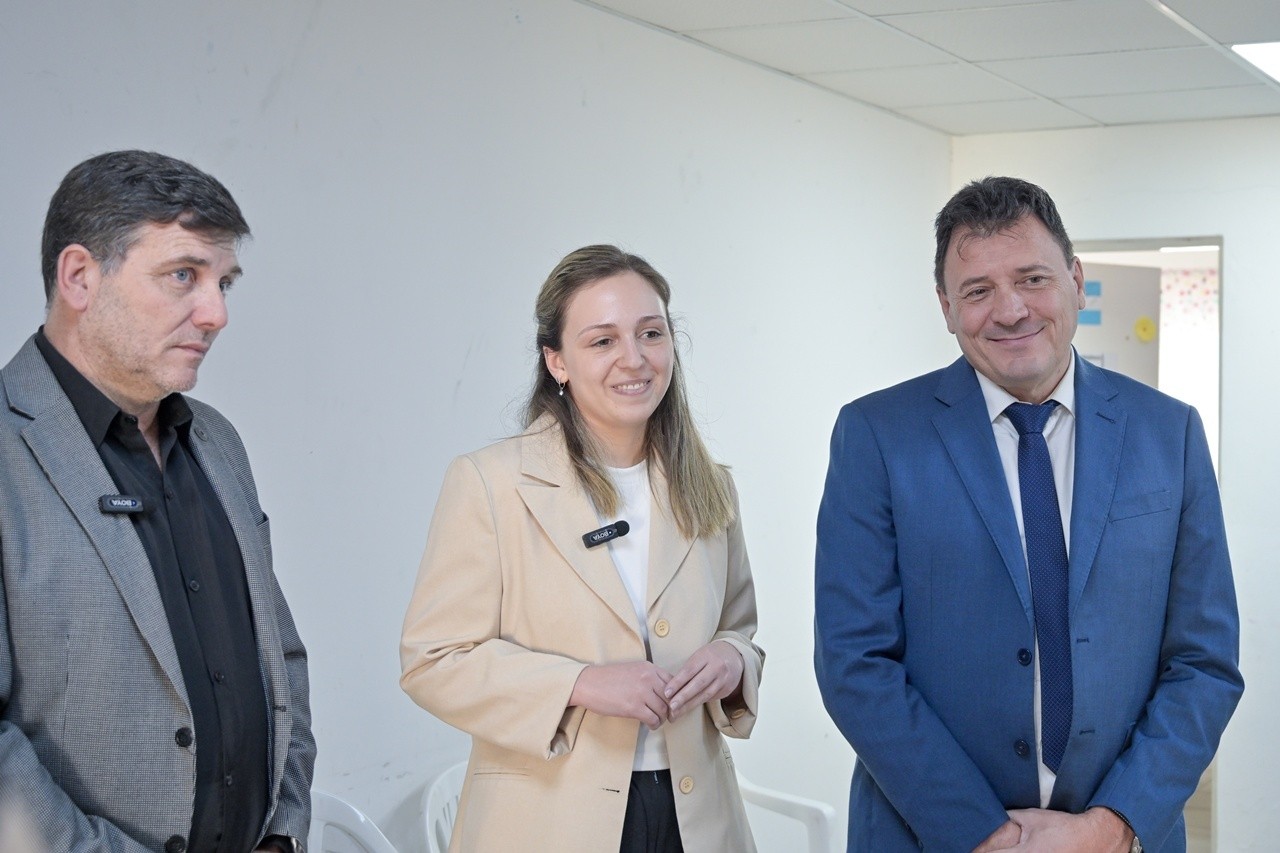 Tres personas con credenciales posan en un entorno corporativo.