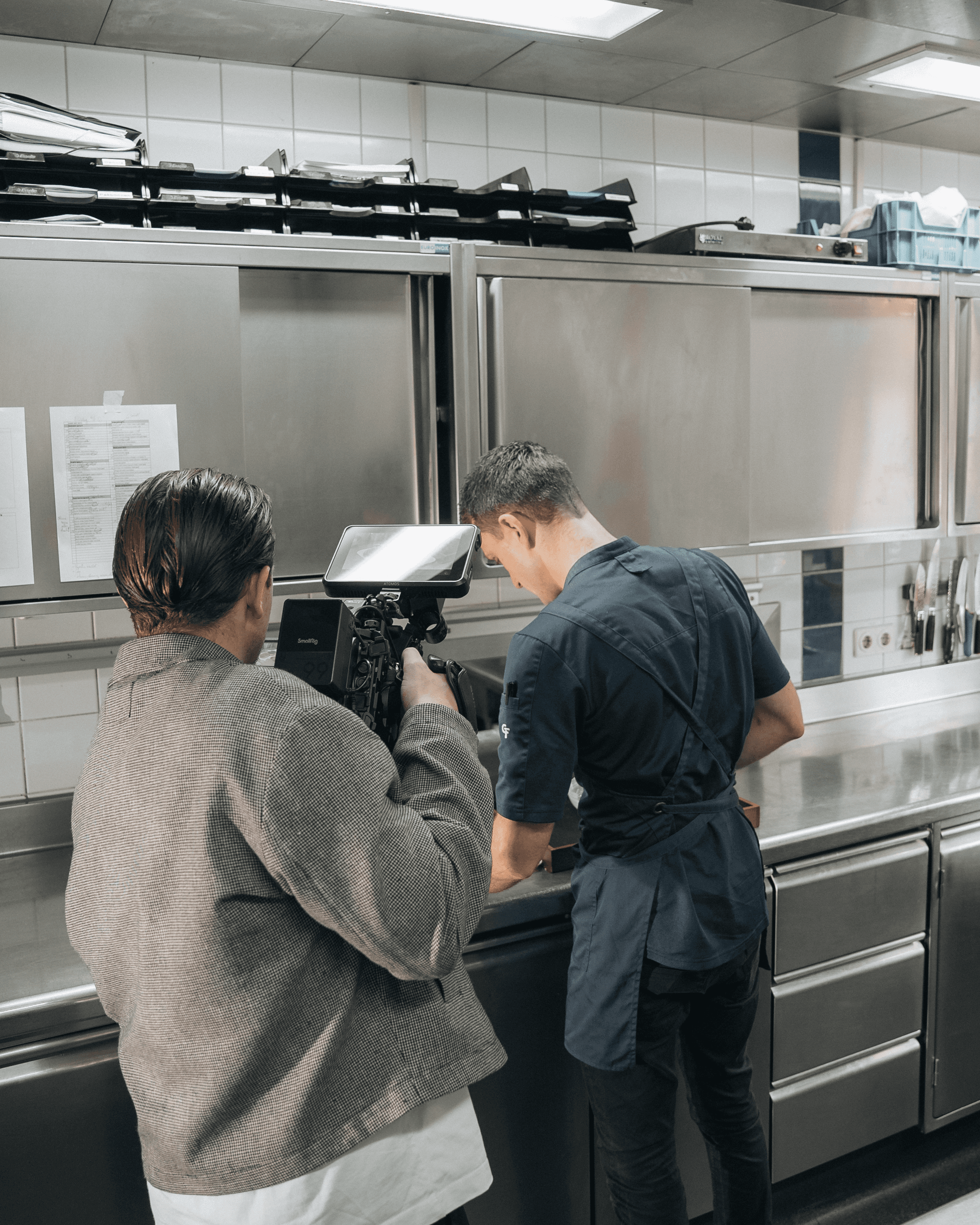 Black and white image of people working at a table with laptops, showing hands gesturing during discussion of digital content displayed on screens, with fabrica® logo in the corner.
