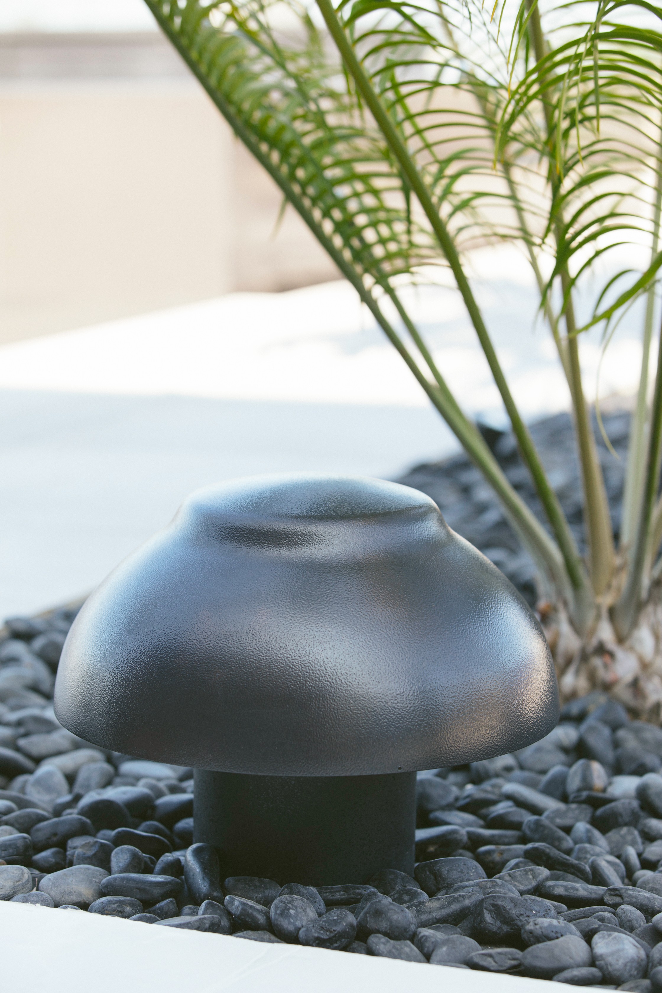 Black mushroom-shaped garden light on black rocks.