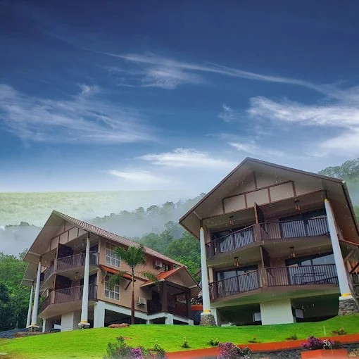 Beautiful hillside cottages at Au Revoir Resort, Kerala, surrounded by greenery and misty mountains, showcasing a serene setting ideal for authentic Ayurvedic wellness retreats.