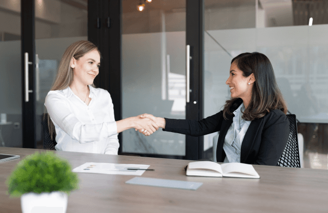 Two colleagues discussing data on a laptop screen.