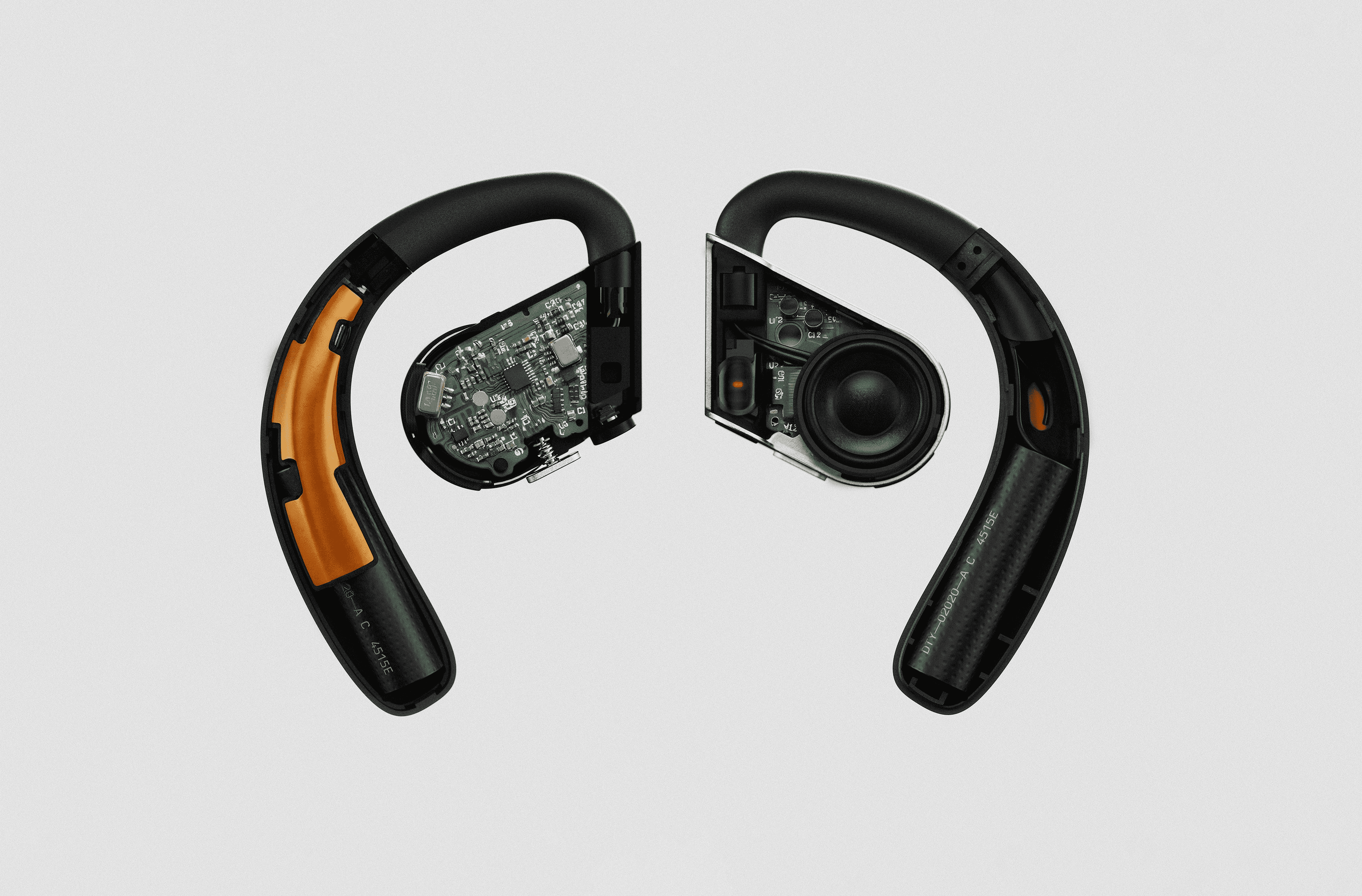 Partially disassembled earphones lying on a white background. The disassembled earphones expose the components inside, like circuitry and batteries.