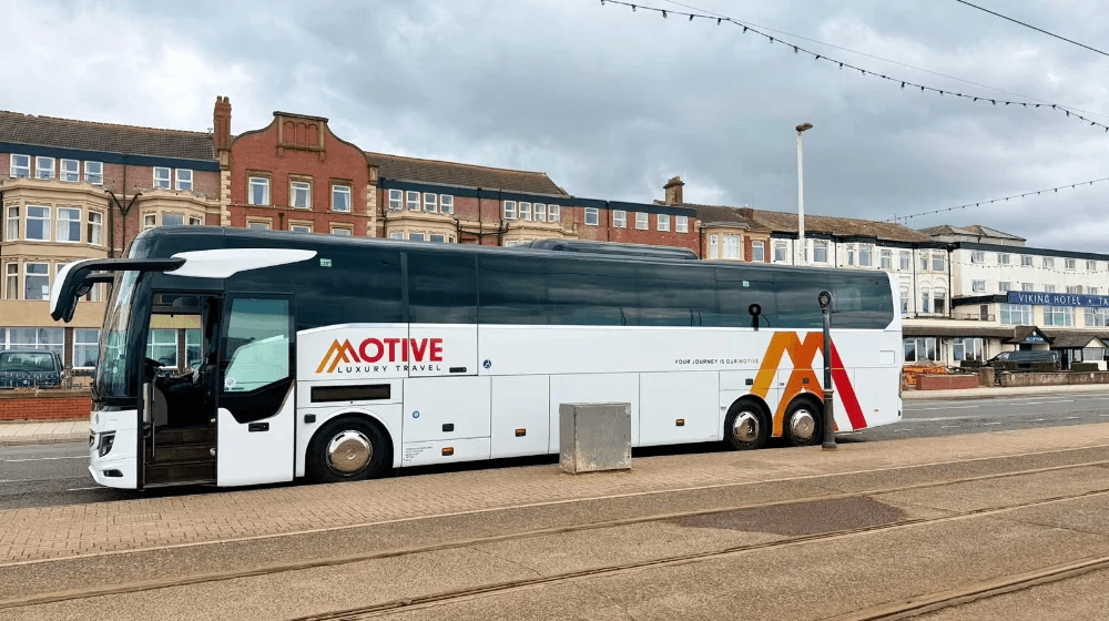 Luxury coach or minibus traveling through scenic landscapes, representing Motive’s professional chauffeur and transport services designed for comfort, reliability, and style.