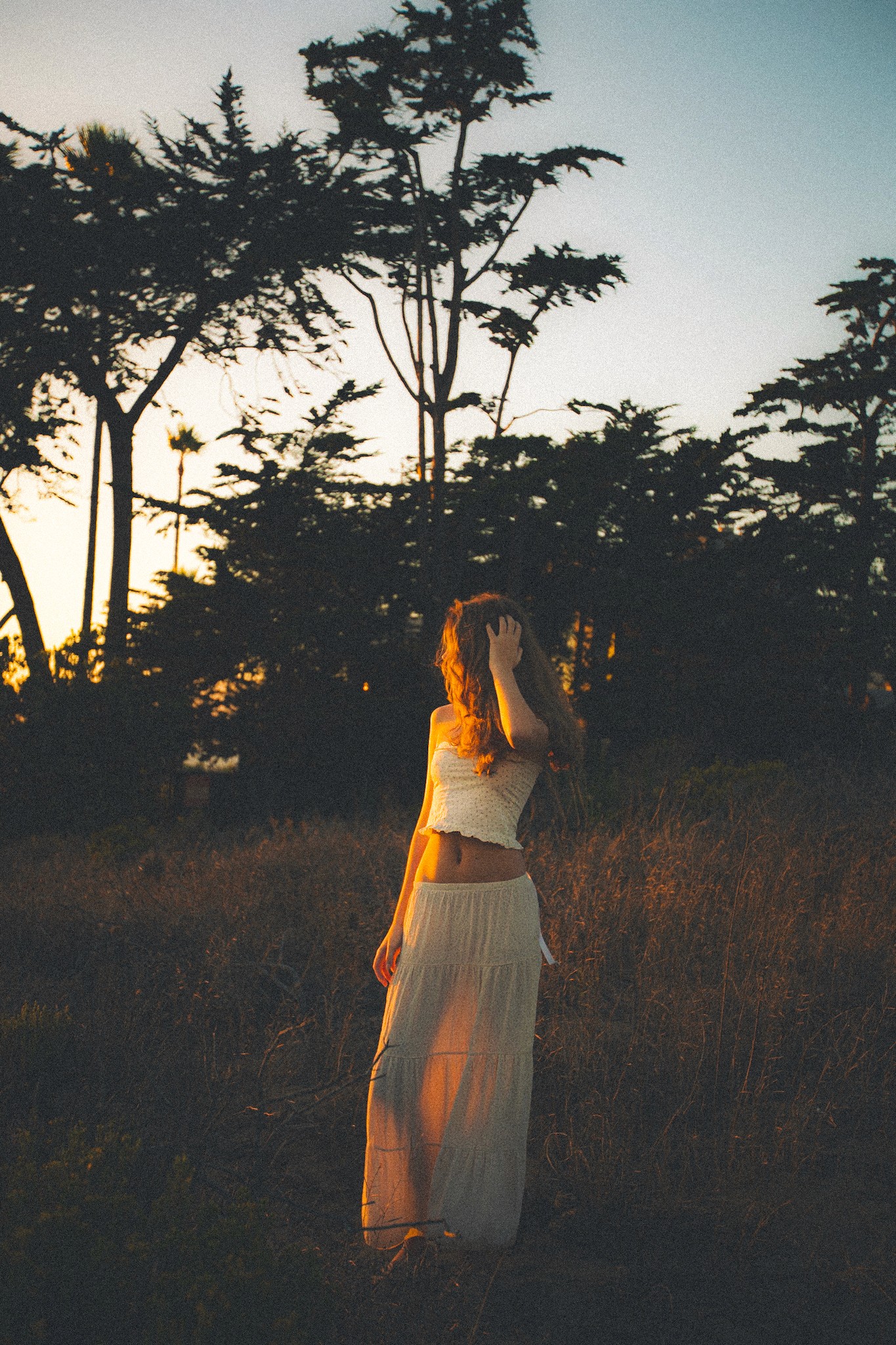 Three people in a field wearing white suits