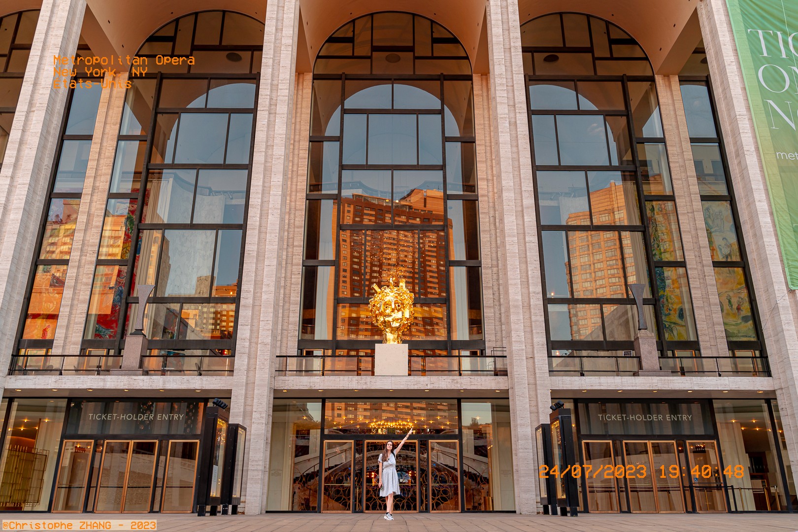 Vue du Metropolitan Opera de New York au coucher du soleil, avec une sculpture lumineuse et des reflets urbains.