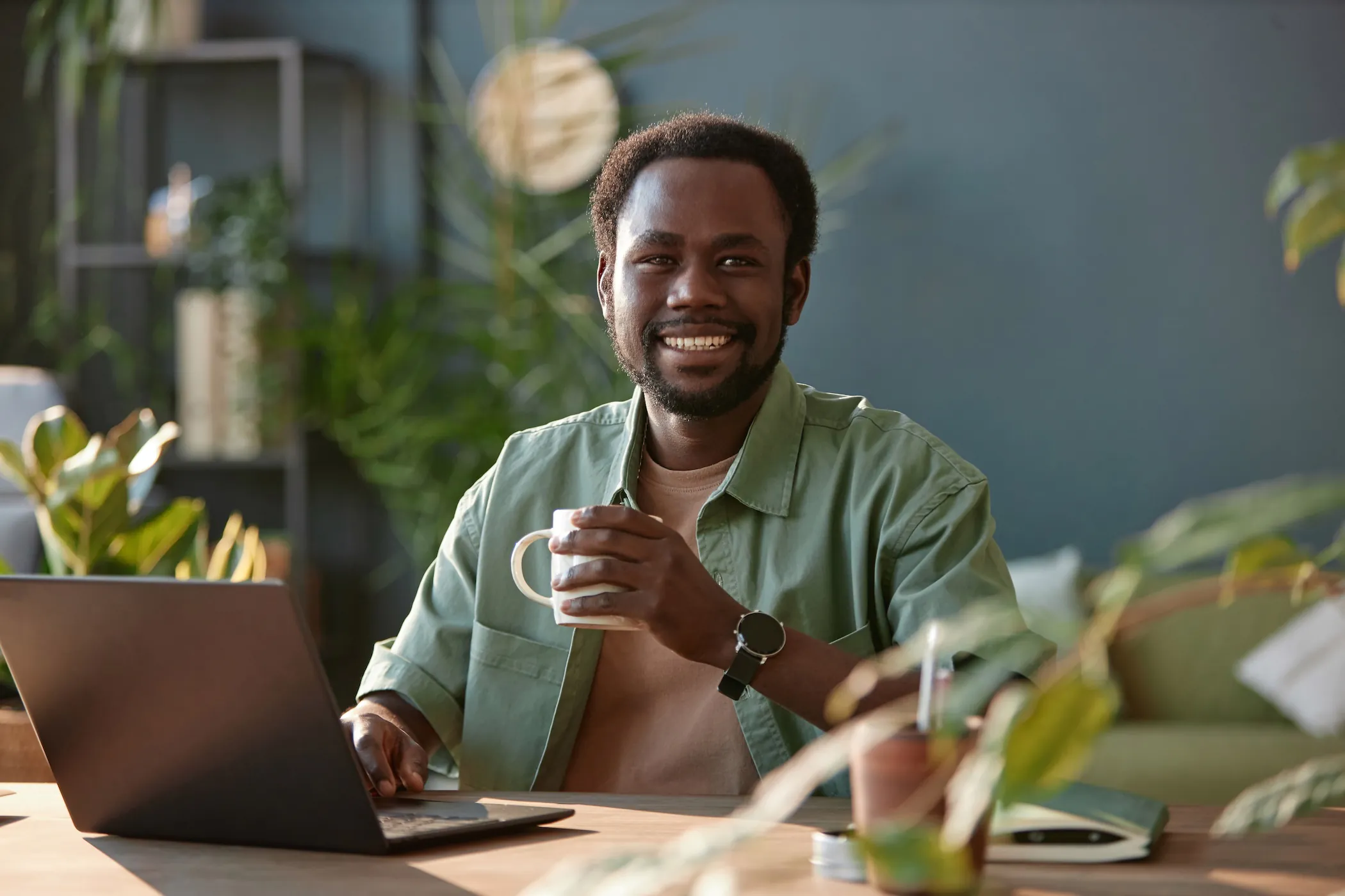 Smiling man with a coffee and laptop