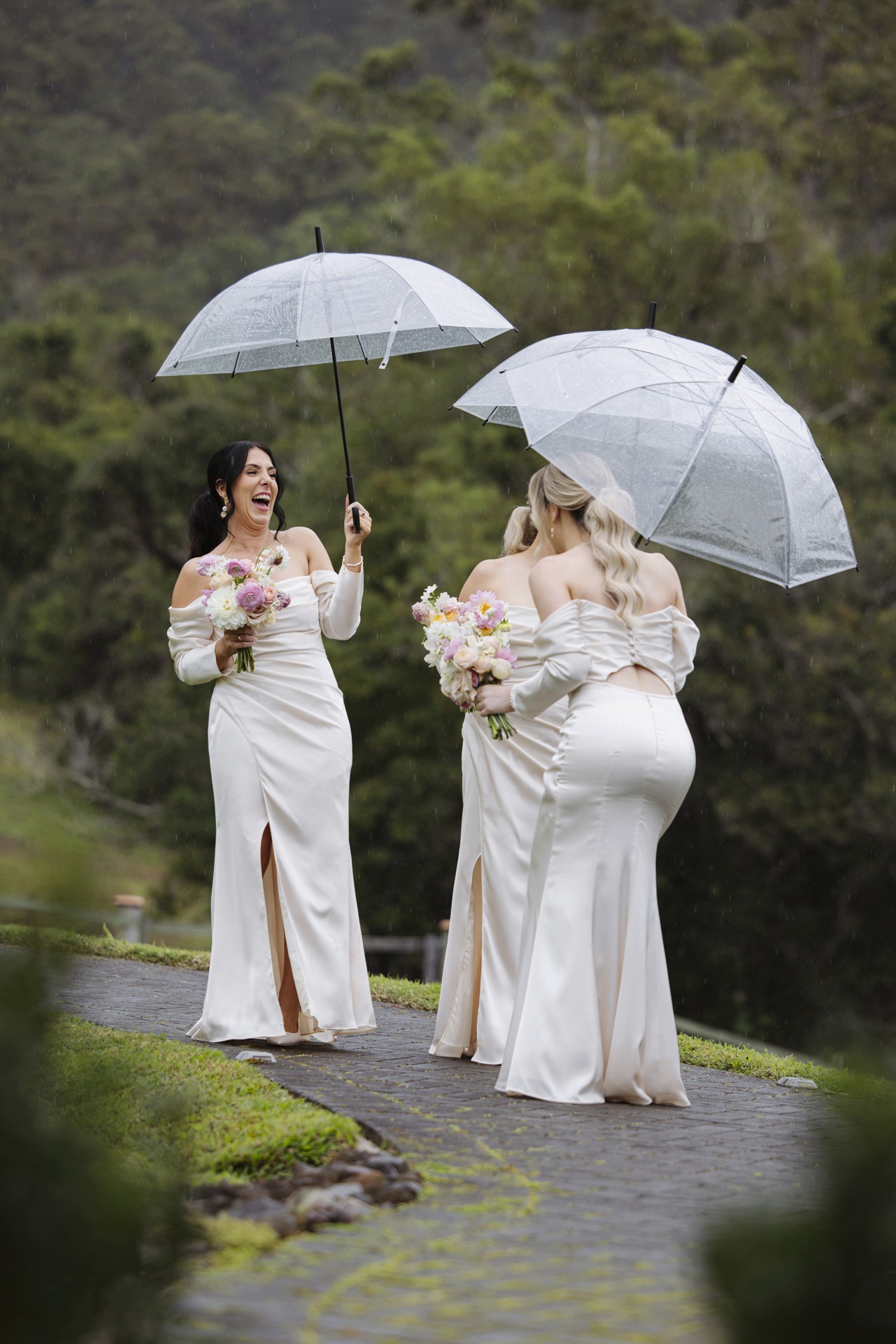 Bridesmaids holding clear umbrellas laughing together