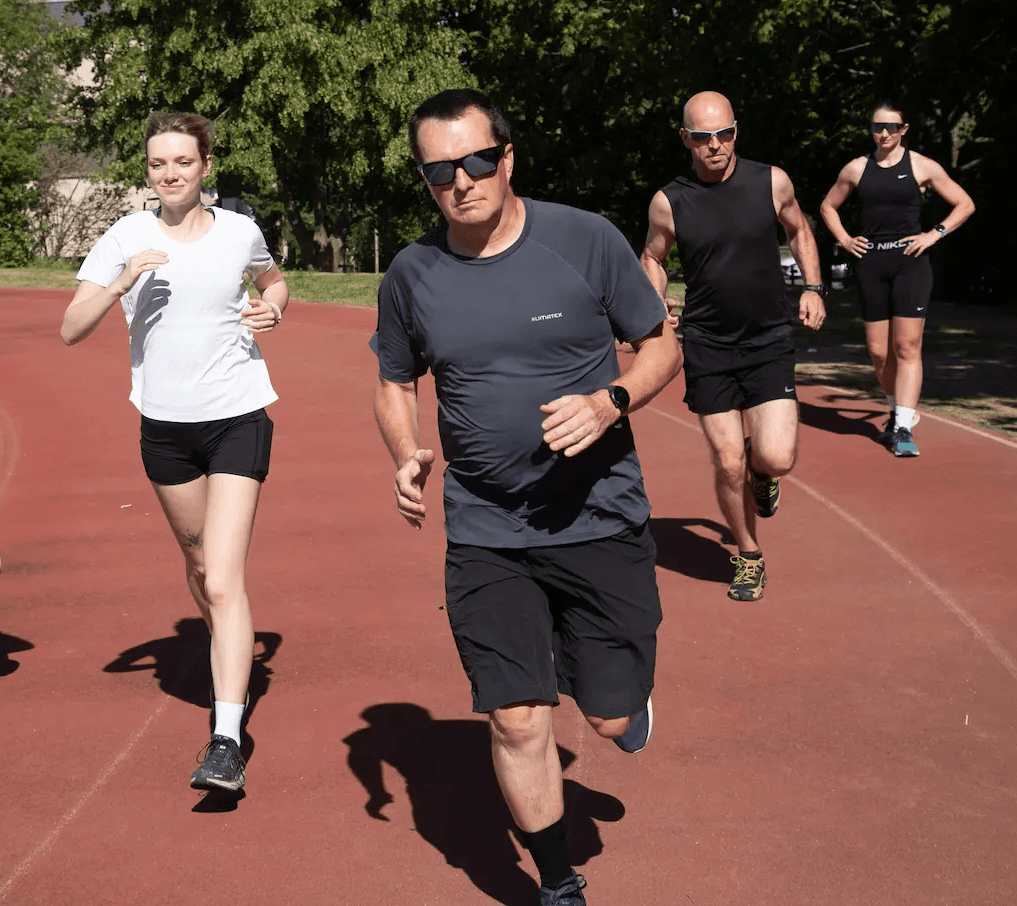 Skupina běžců trénuje na červené atletické dráze