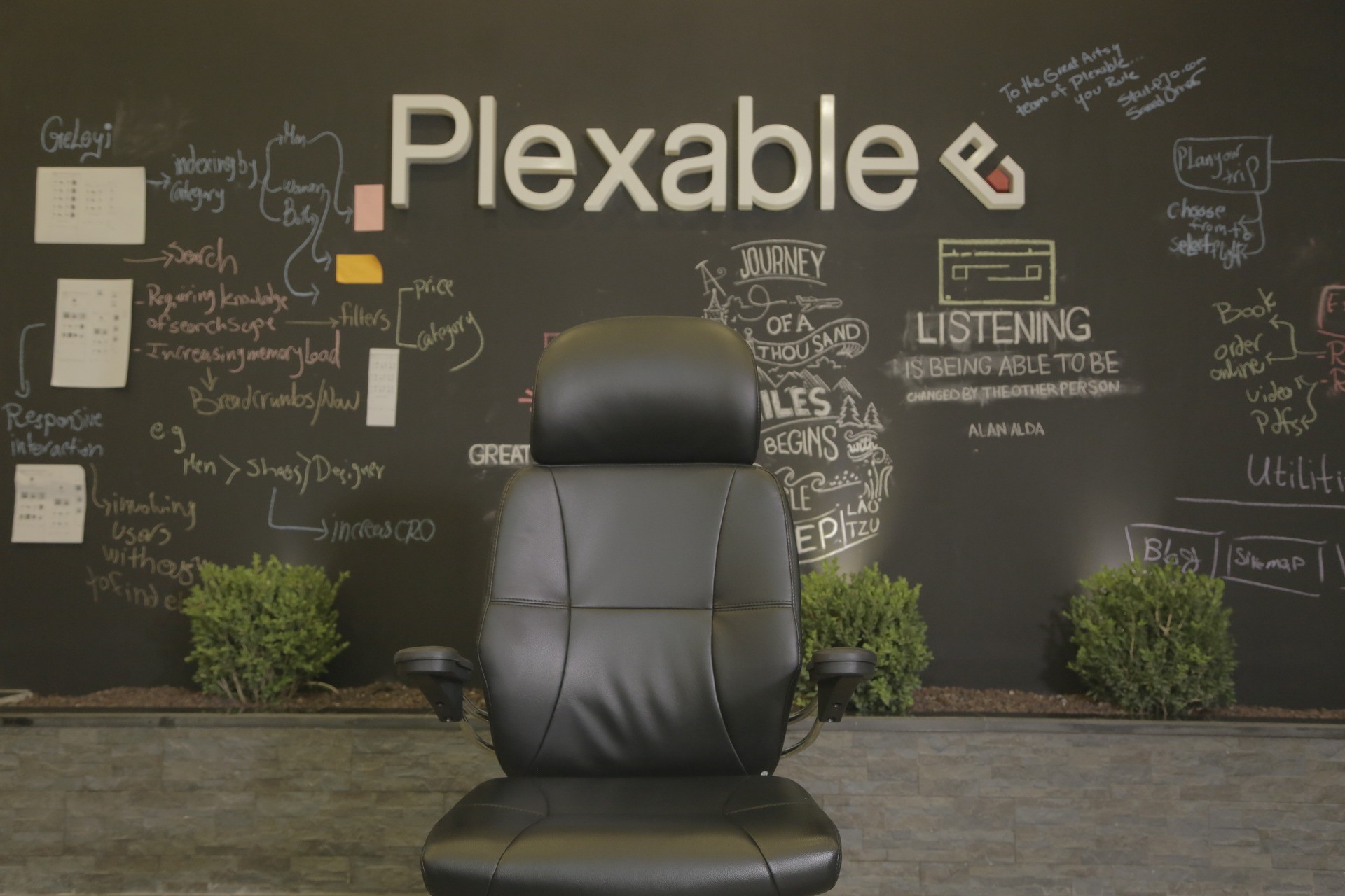 Plexable logo and product notes on a blackboard wall behind an office chair