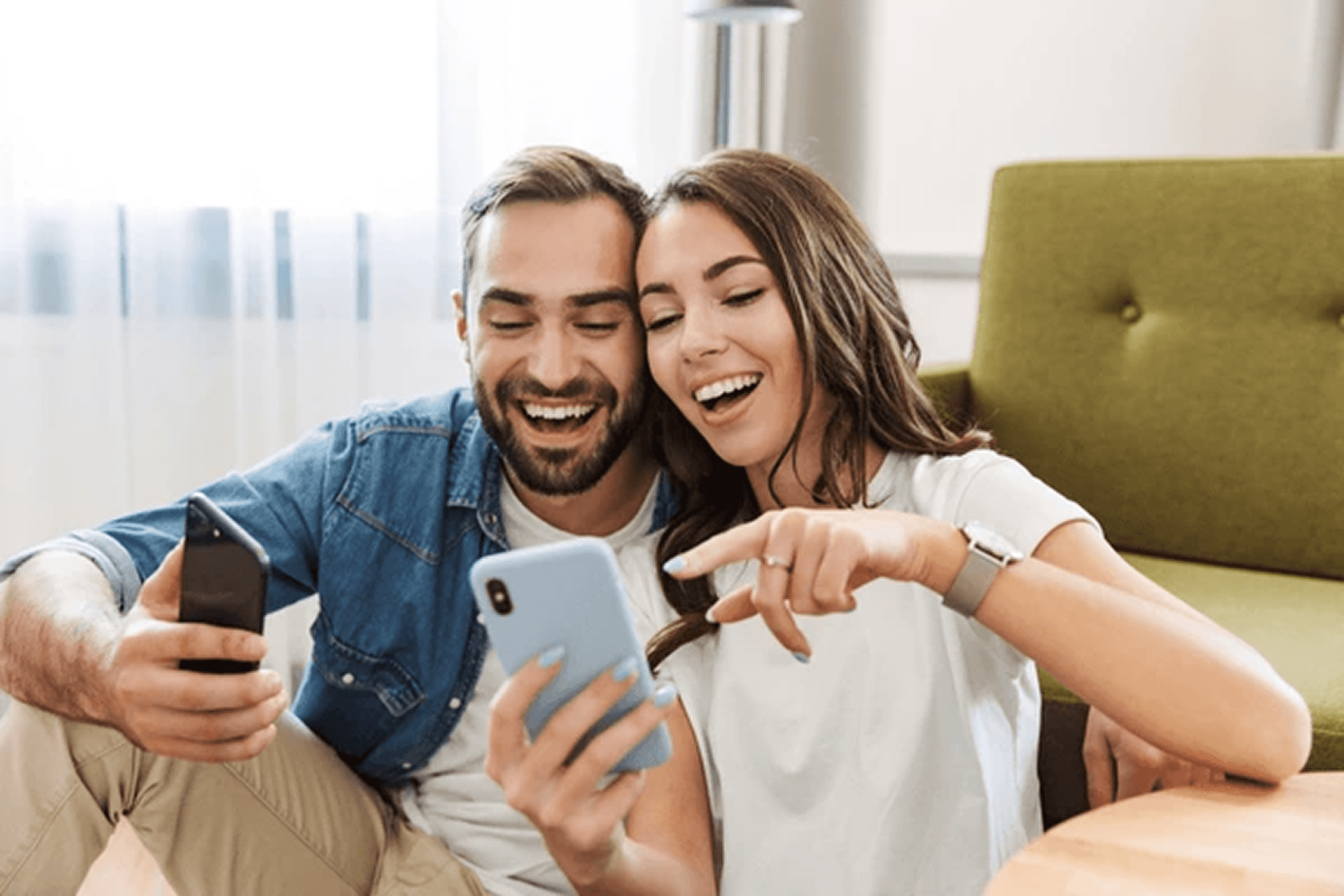 woman holding a phone and man looking at the phone. both are smiling