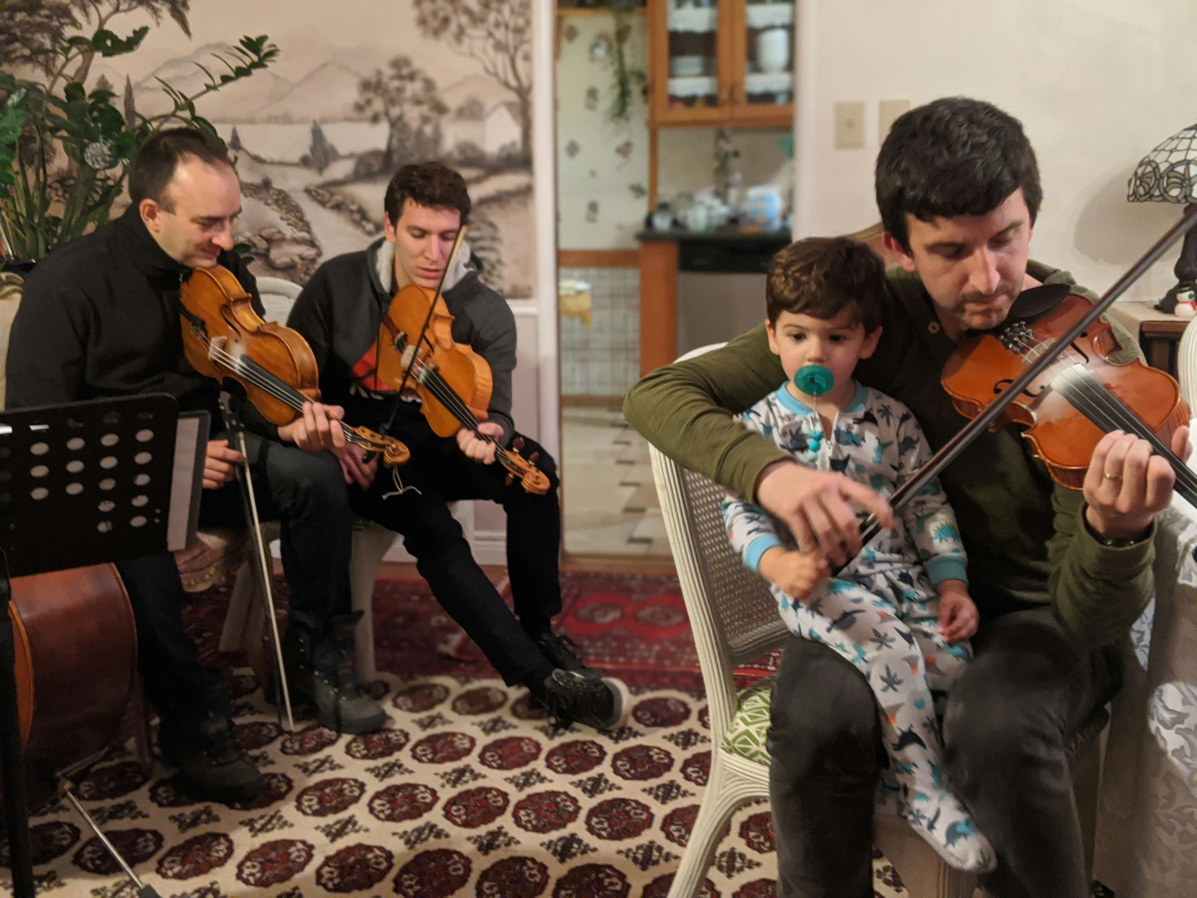 a group of men playing violin in a living room