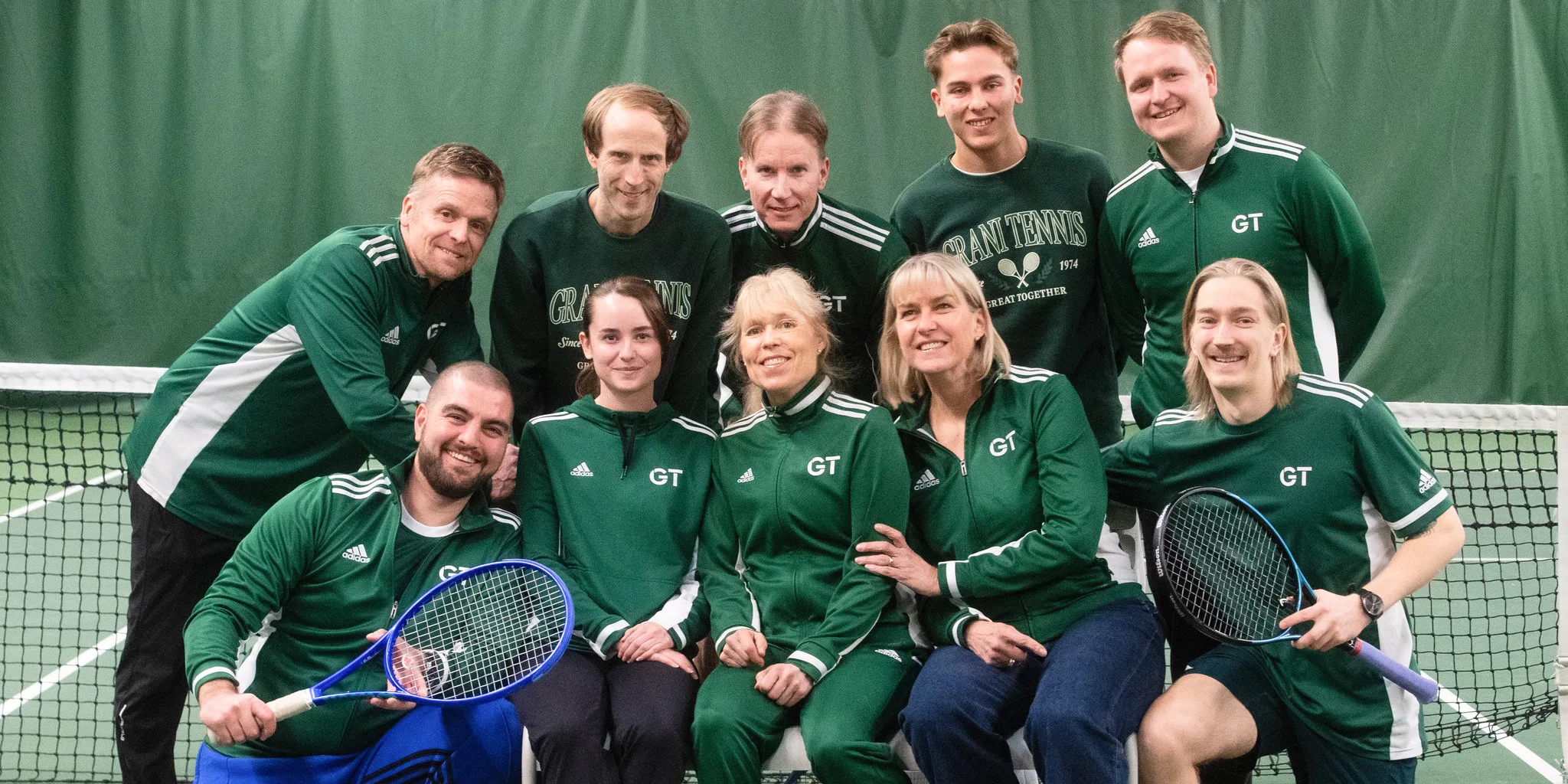 Pelaajia istumassa penkillä tennismailat sylissä