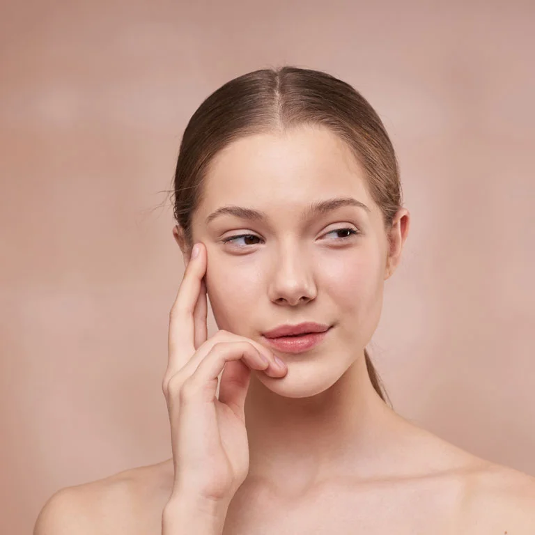 Woman touching her face after facial treatment, representing professional facials and chemical peels for brighter, smoother, and hydrated skin in Los Angeles.