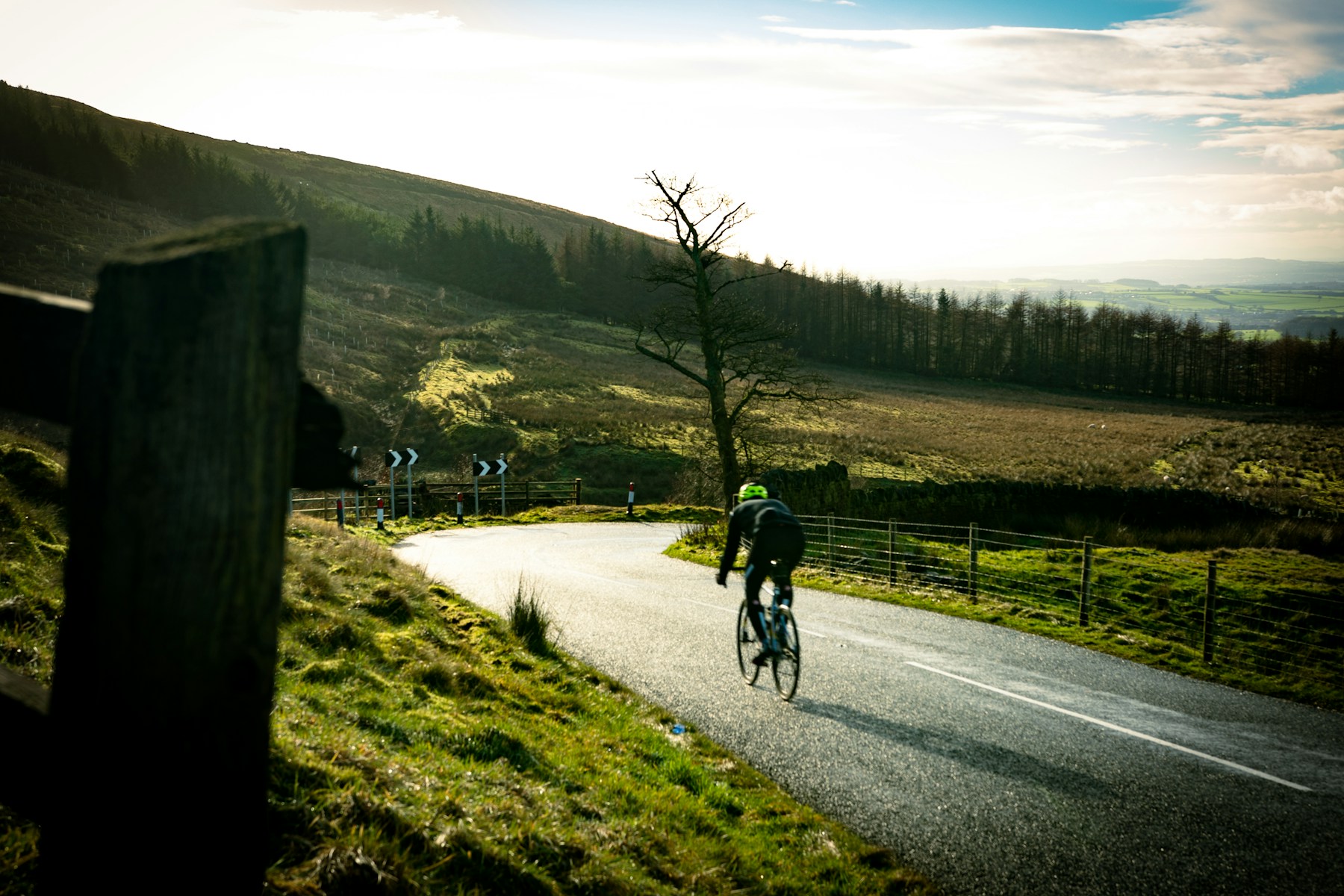 A cyclist riding a winding road across open moorland