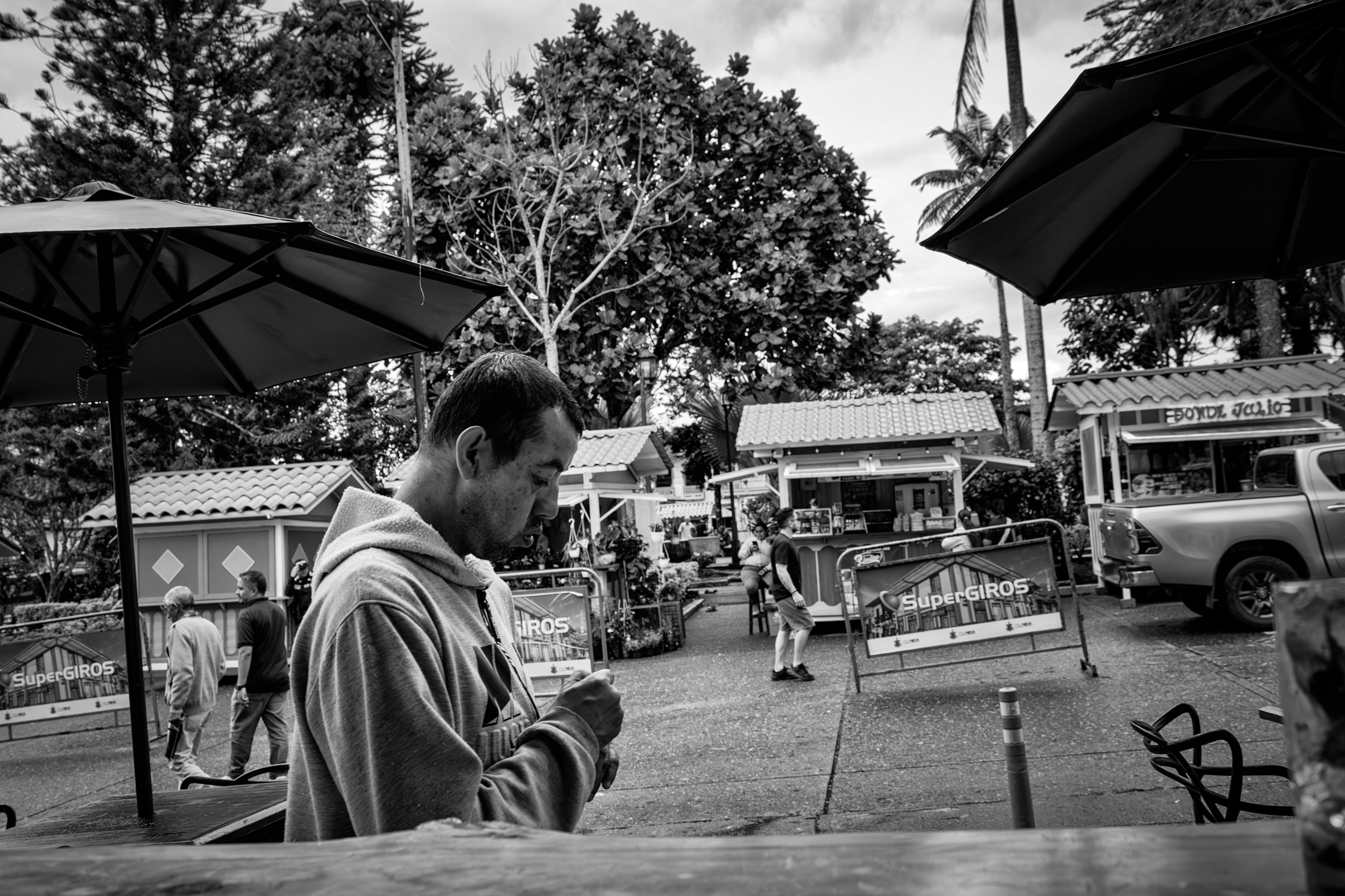 Rainy street scene with people passing by a bar window.