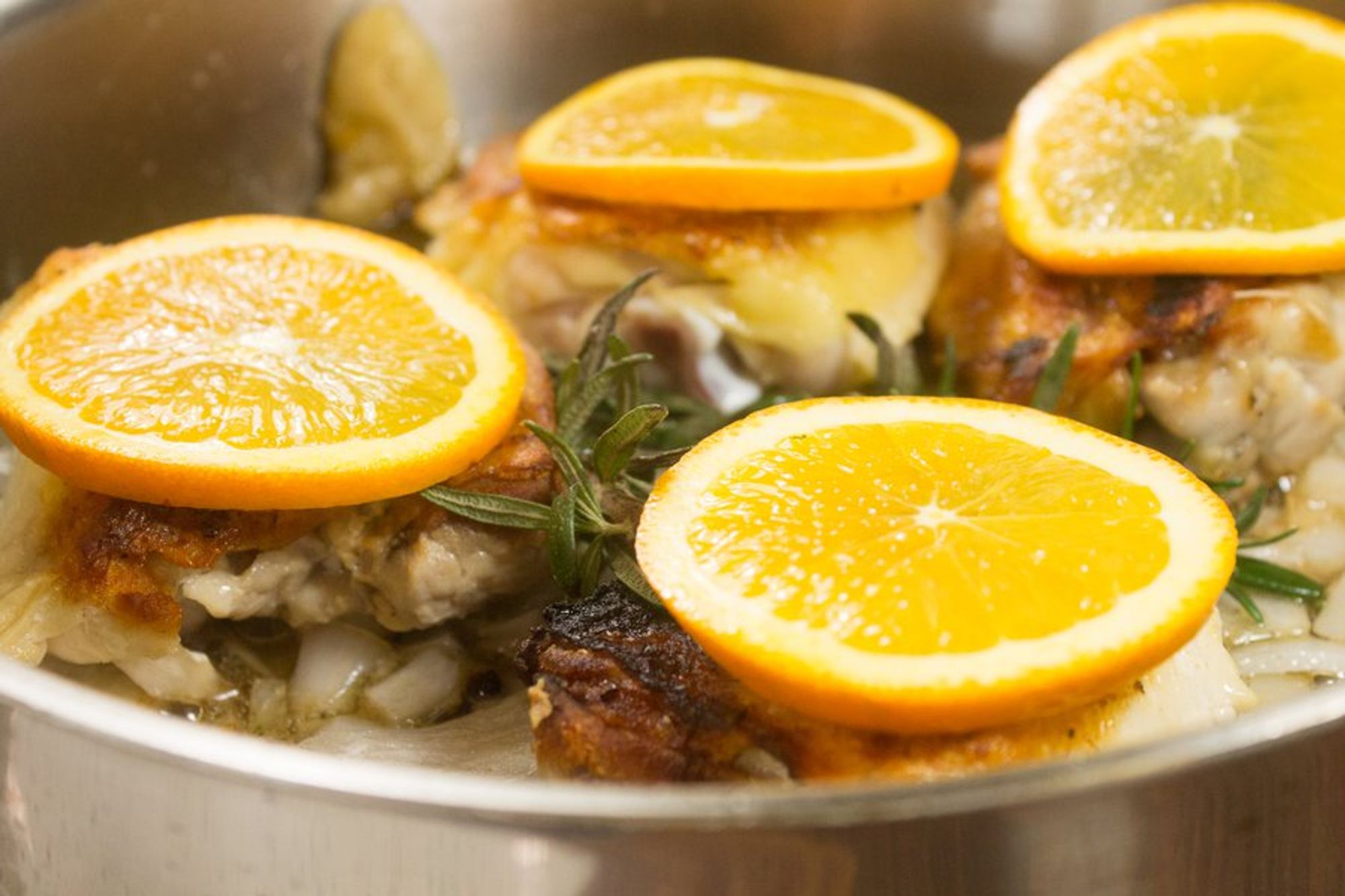 cooked chicken thighs topped with sliced orange