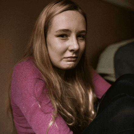 Young woman sitting with knees up, looking upset, representing feelings of sadness and the caring support available through HeadHealth therapy.