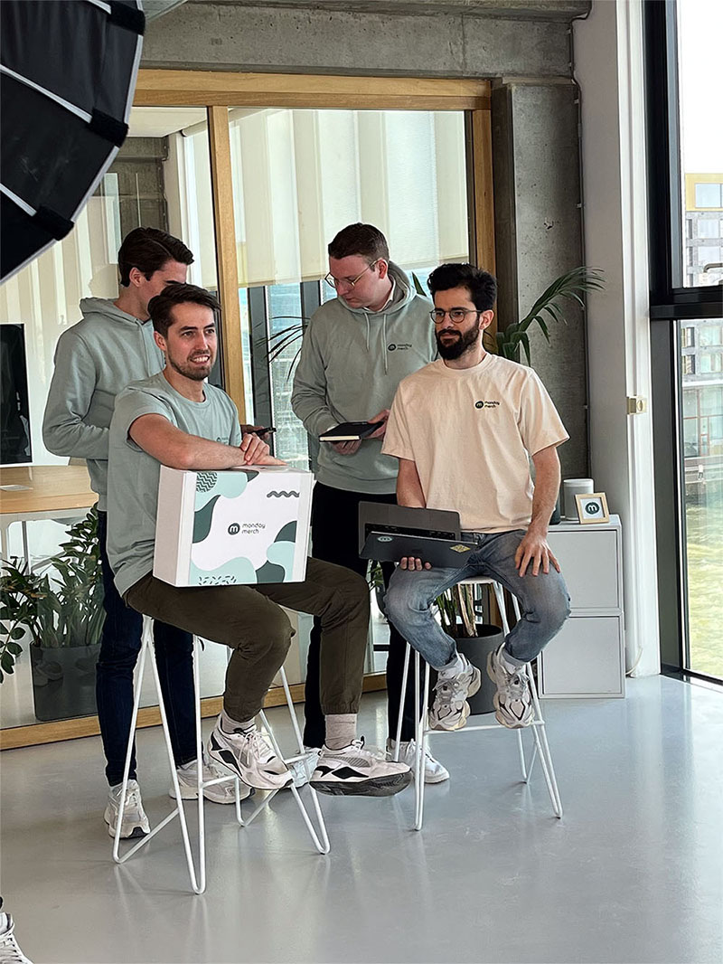 Four people gathered in a bright room, working together at a laptop on a small table.