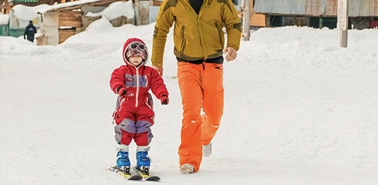 Enfant qui apprend à skier avec son père