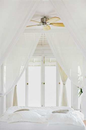 A bright, airy room with high white ceilings, large windows, and a decorative ceiling fan.