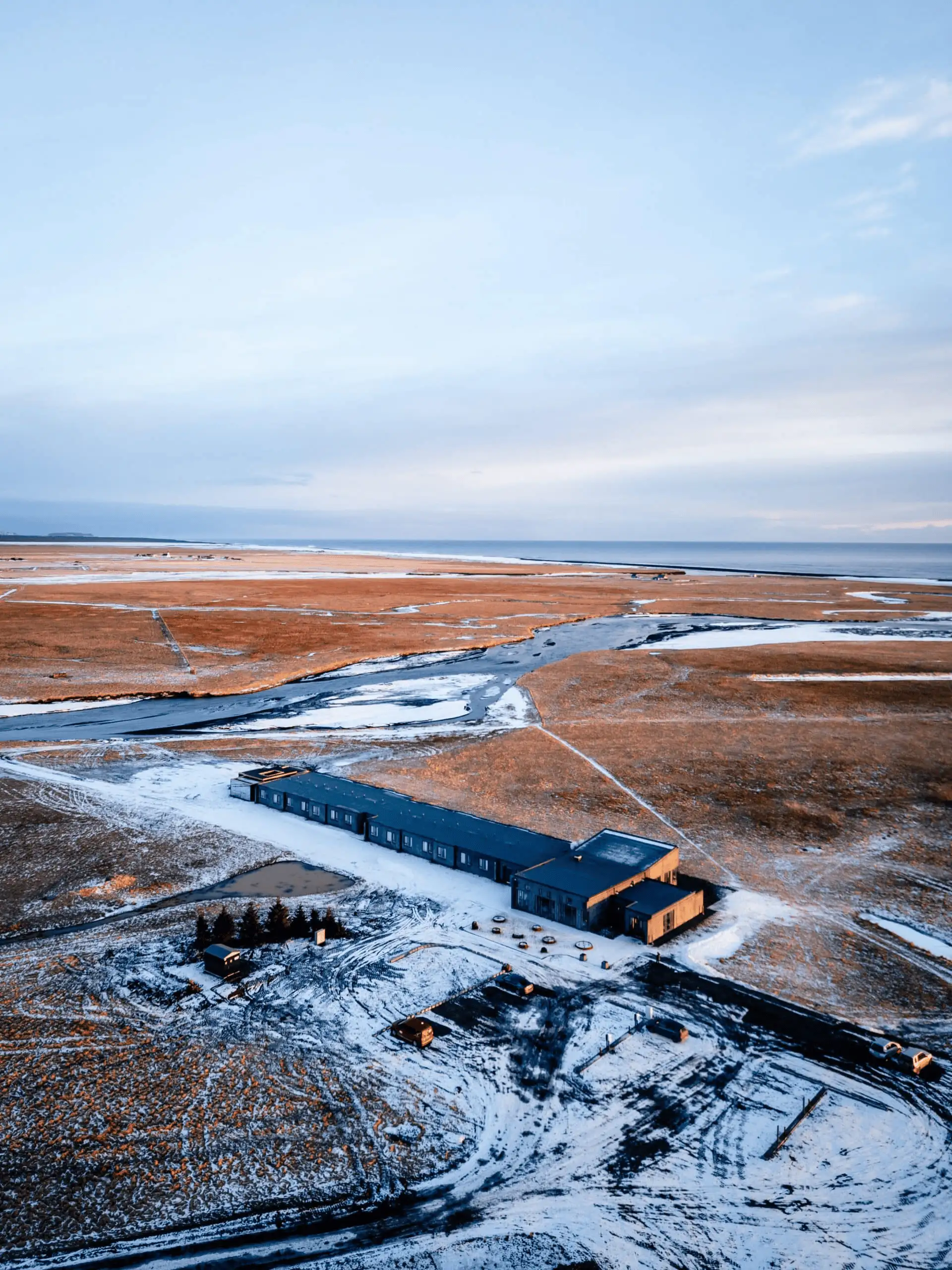 Aerial view of the hotel on a wide, snow-dusted plain stretching to the sea