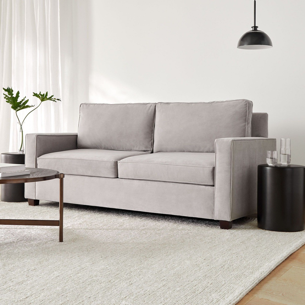 Light gray 61-inch sleeper sofa in a minimalist living room with a black lamp