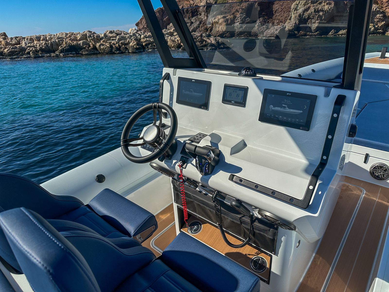 White Rock 36 speedboat with captain at helm cruising calm blue waters near Paros coastline with hills in background.