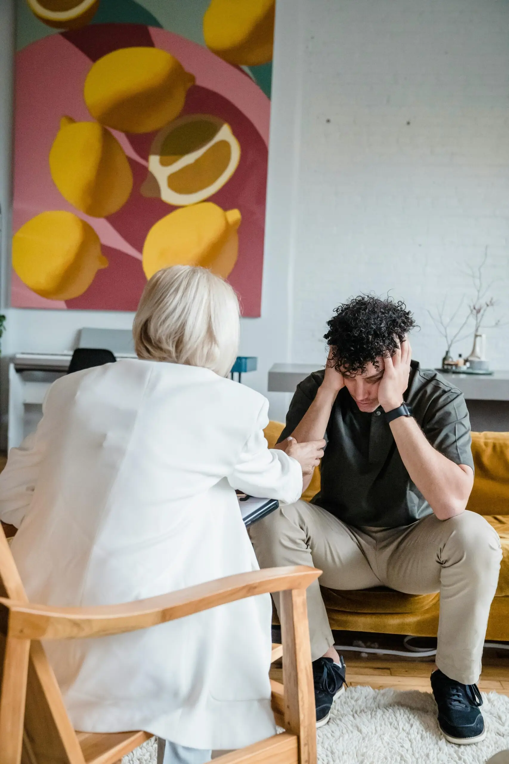 Therapist consoling a distressed man in a therapy session.
