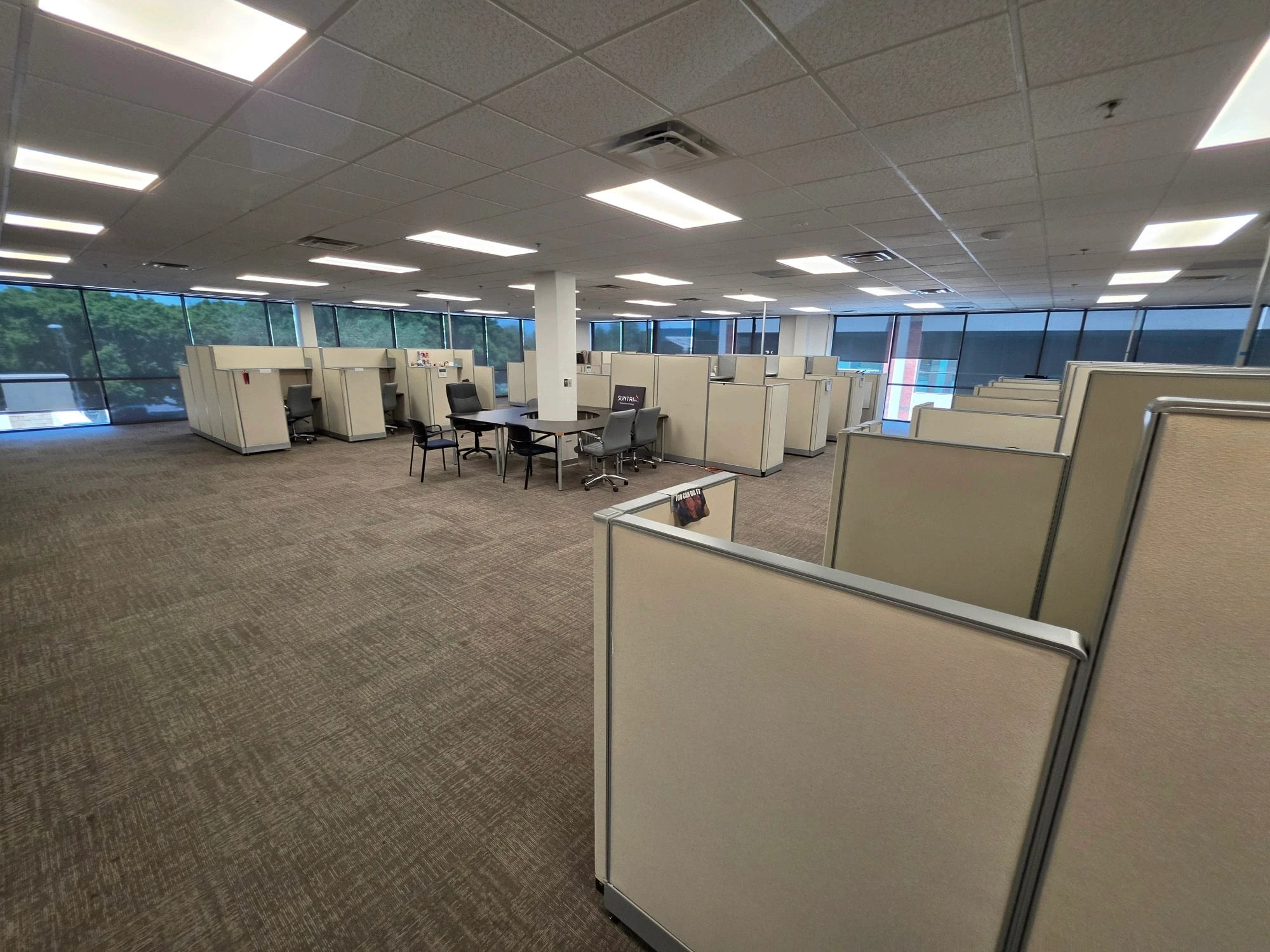 office cubicles in a large corporate workspace with bright ceiling lights.