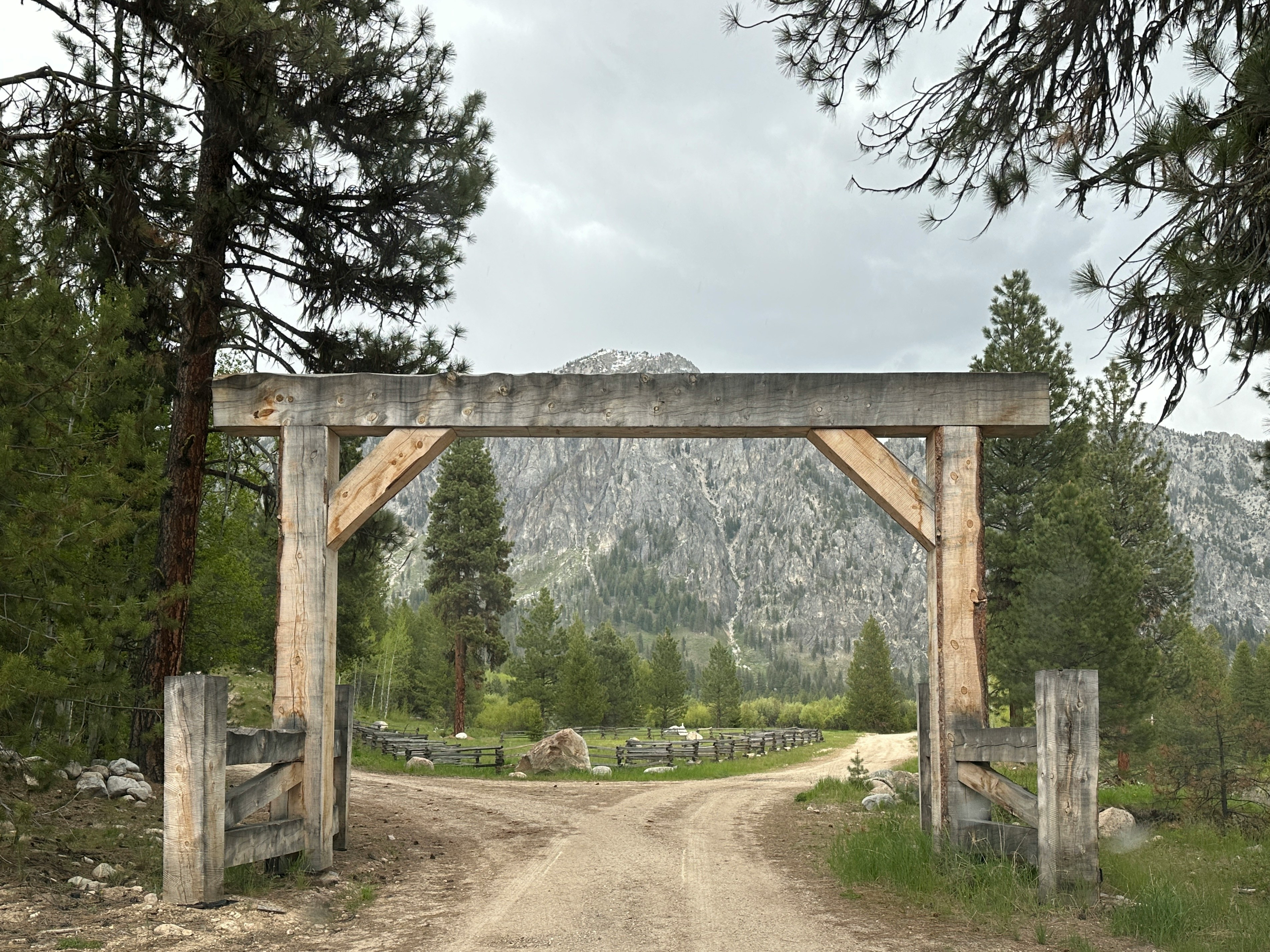 a dirt road that has a wooden arch over it