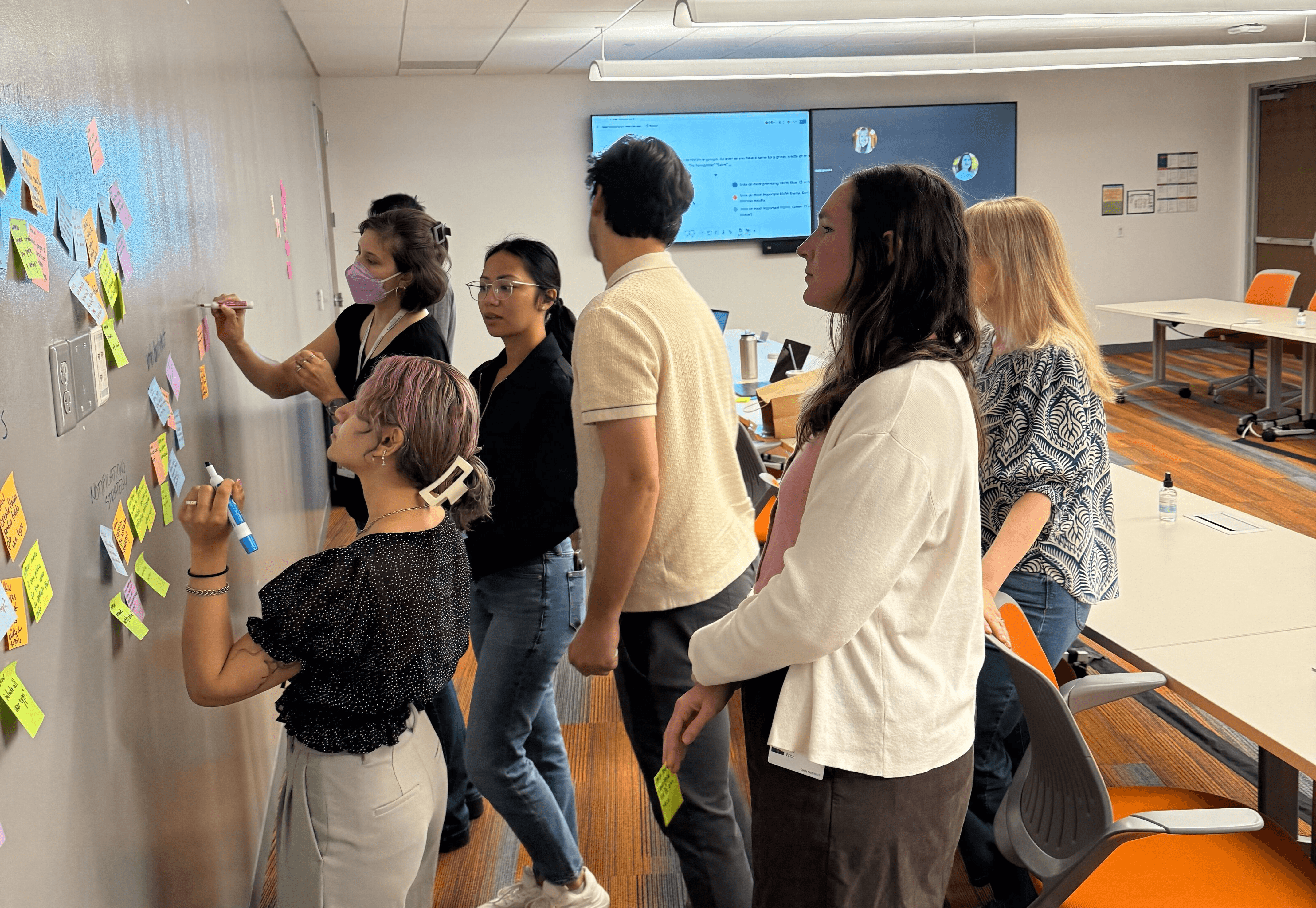 Group of designers putting down sticky notes on wall