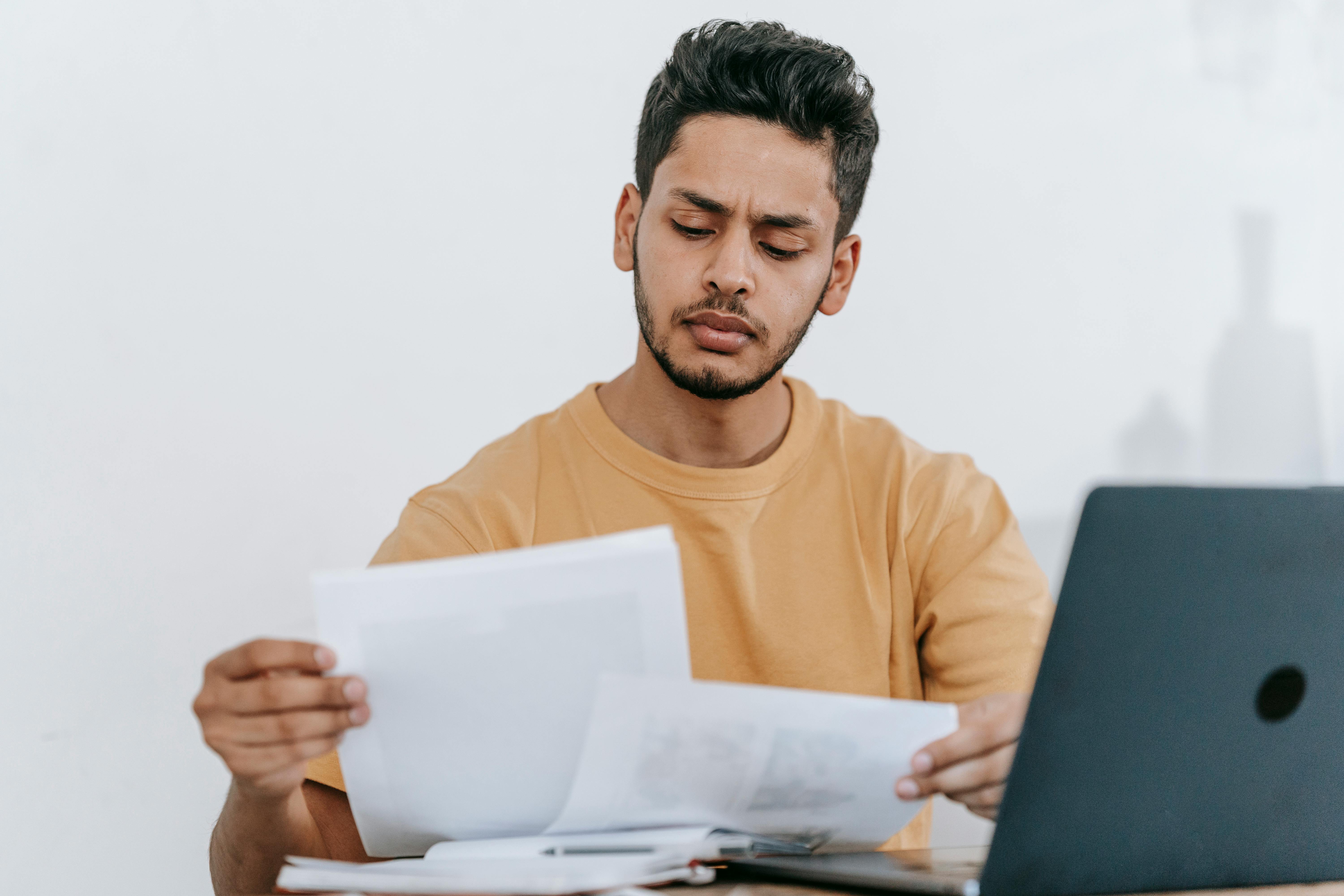 Human resource manager sitting in front of a laptop reading papers