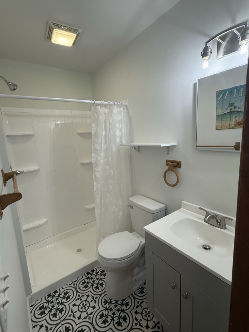 Finished bathroom with new shower surround, vanity, lighting and patterned tile floor