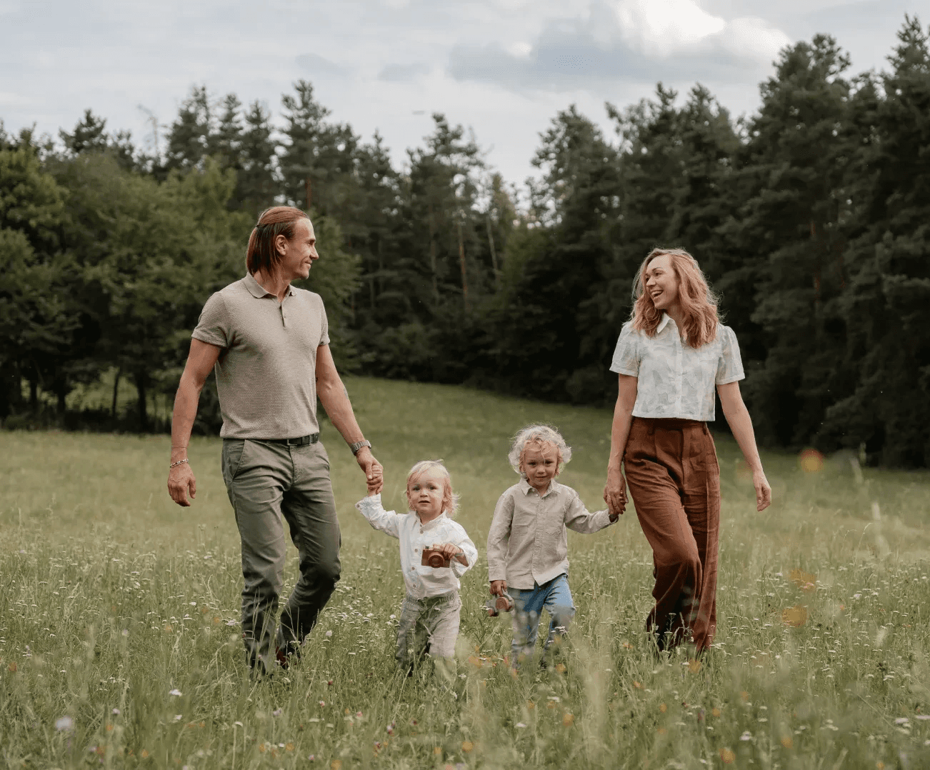Rodina se dvěmi dětmi na procházce po zelené louce