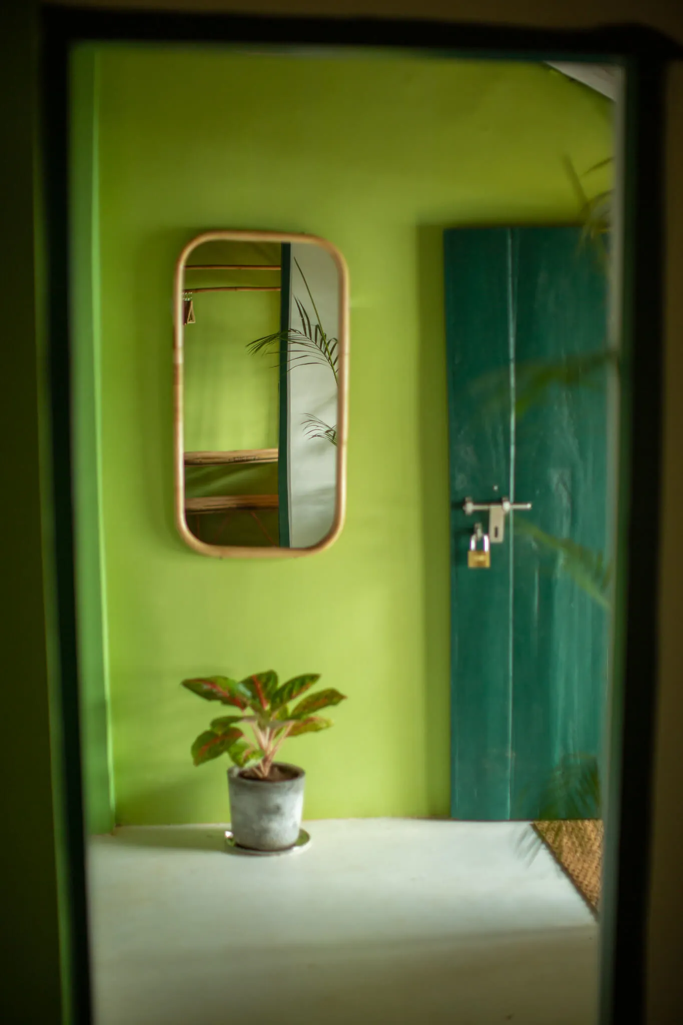 Lime-green passage with a cane mirror at Casa Jaali