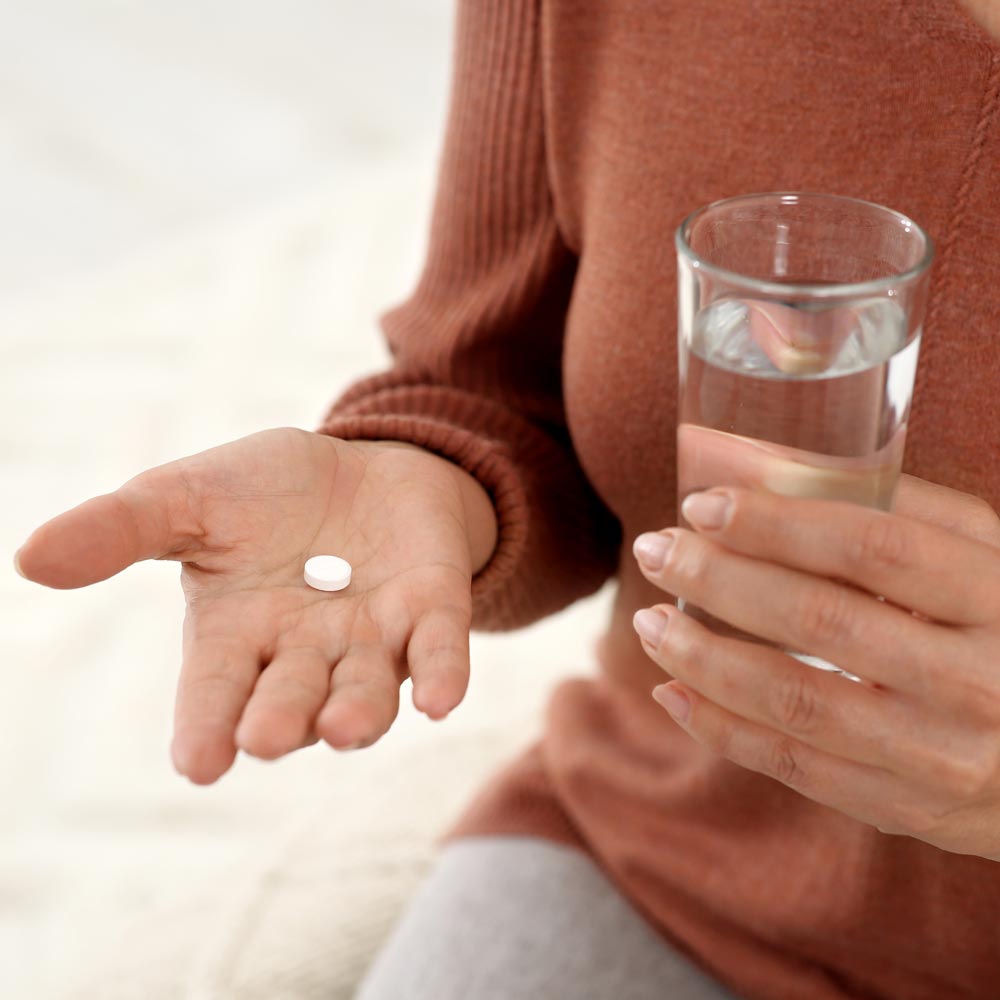 Woman holding pill and glass of water