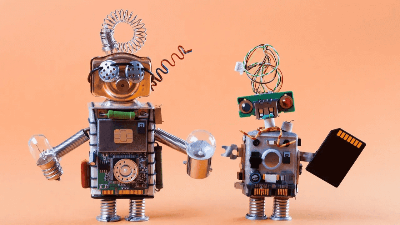 Two whimsical robots made from electronic components, facing each other playfully.