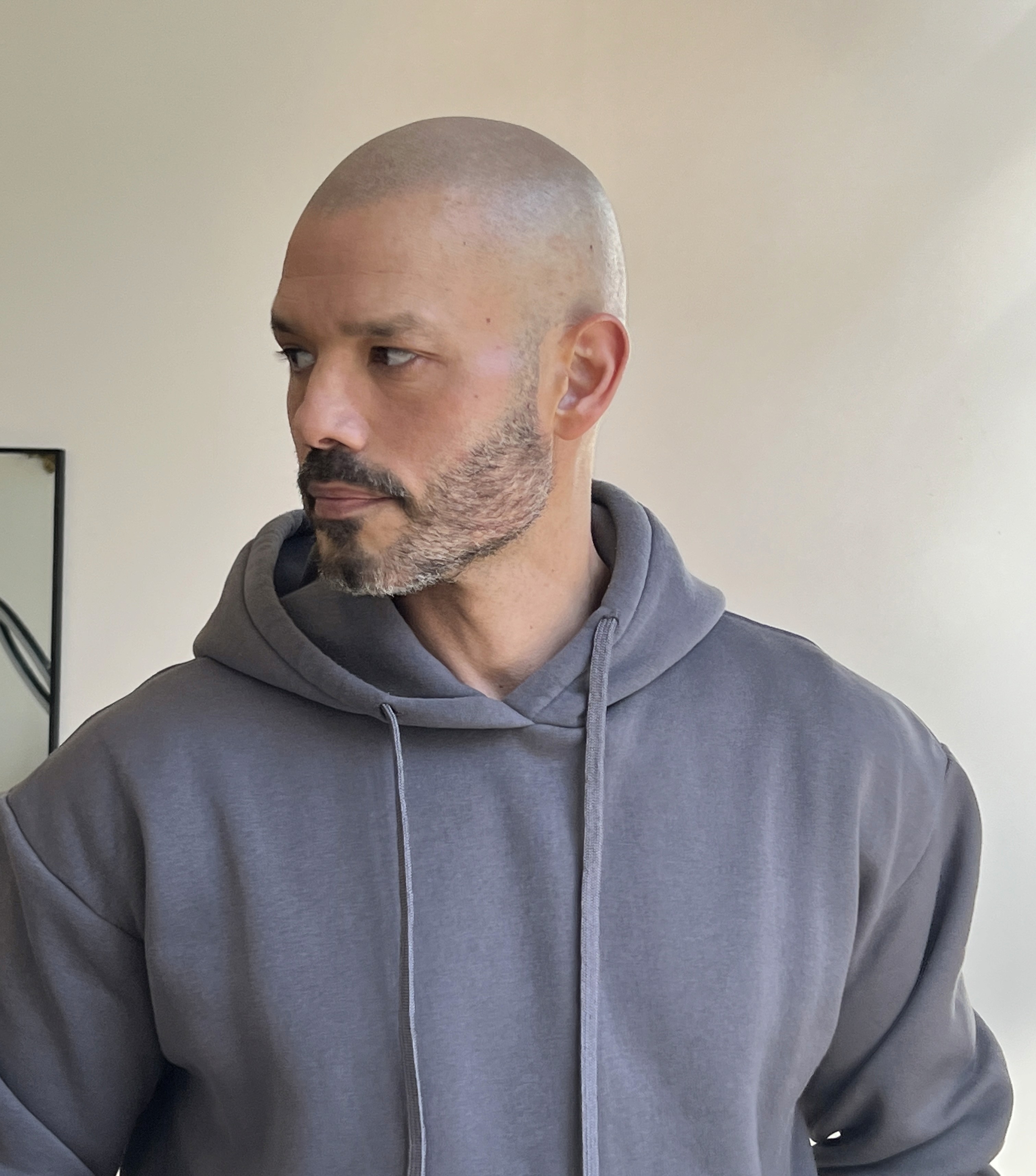 A person with glasses and gloves is tattooing on a client's arm in a well-lit studio.