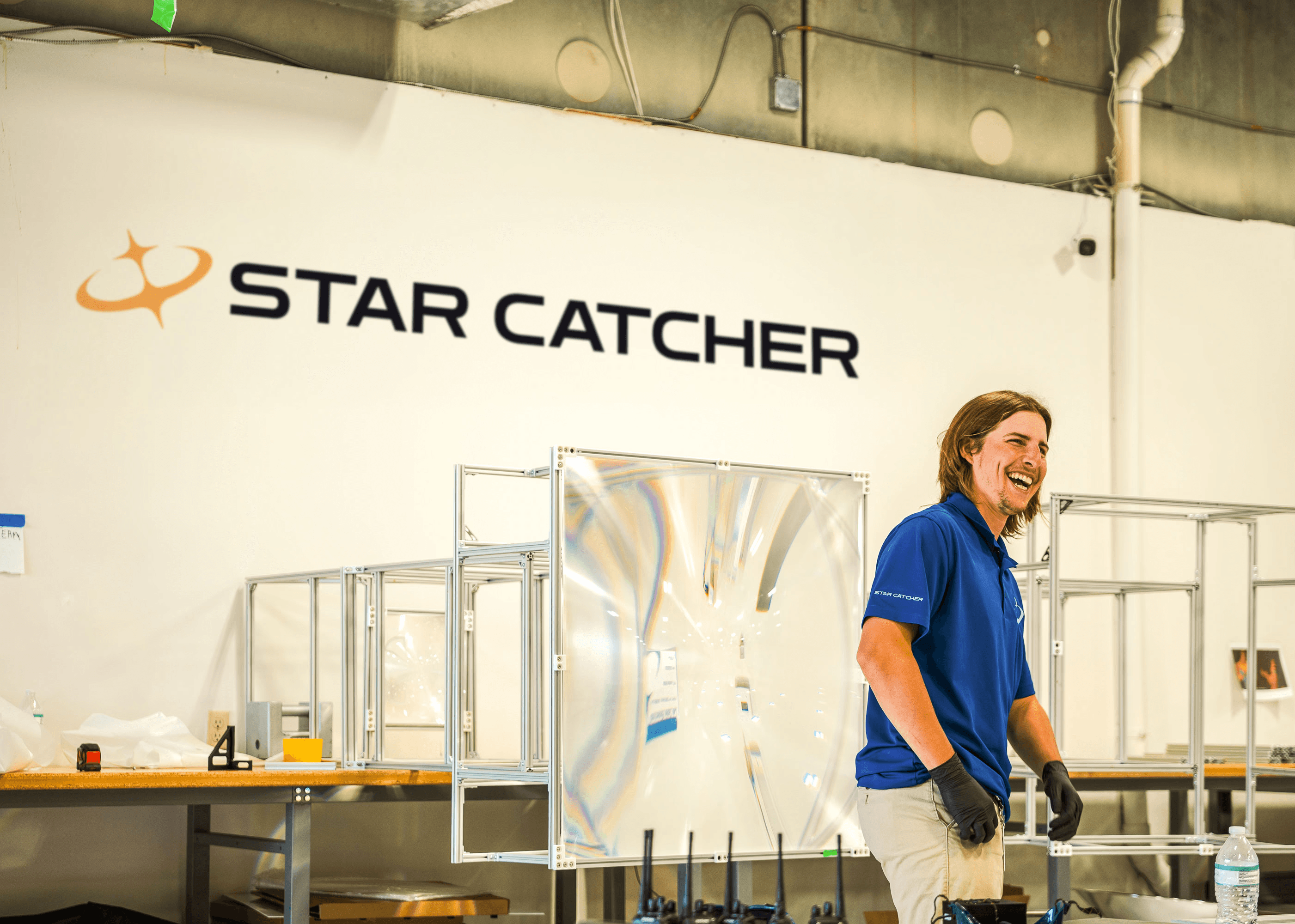 Star Catcher engineer laughing with fresnel lens hardware in background at manufacturing facility